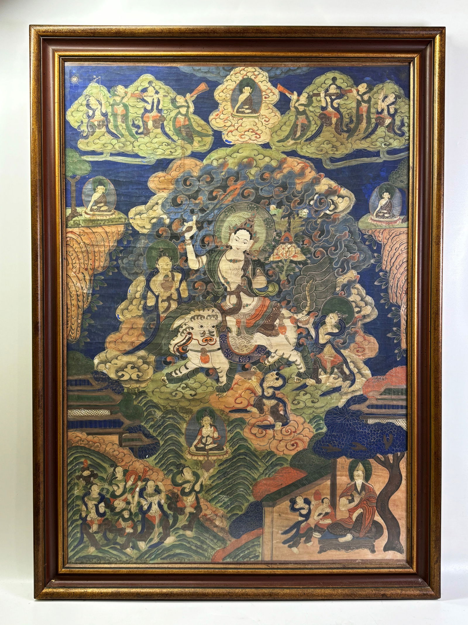 Large Tibetan Seated Manjusri Thangka; Framed: Large Tibetan Manjusri with sword Thangka, the Bodhisattva seated on a Mythical Animal and surrounded by figures and scenes; framed to the edges of the art. Height of art 35 inches X width of art 24 i