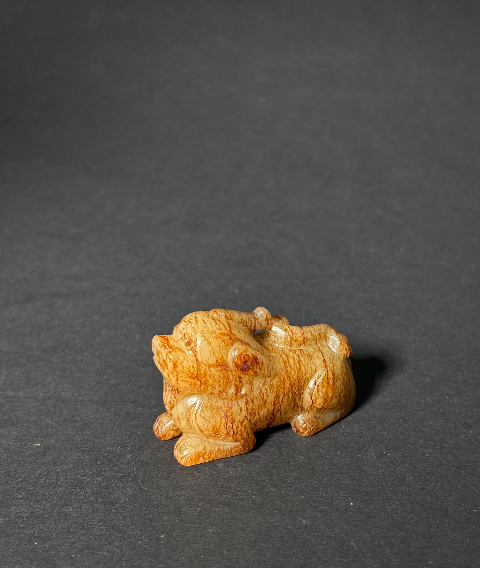 Chinese Pale Celadon & Russet Jade Qilin Toggle: Chinese Pale Celadon & Russet Jade Qilin Toggle; the seated auspicious animal with top horn touching double curled tail and forming a suspension loop. Height 1 1/4 inches X width 2 inches.