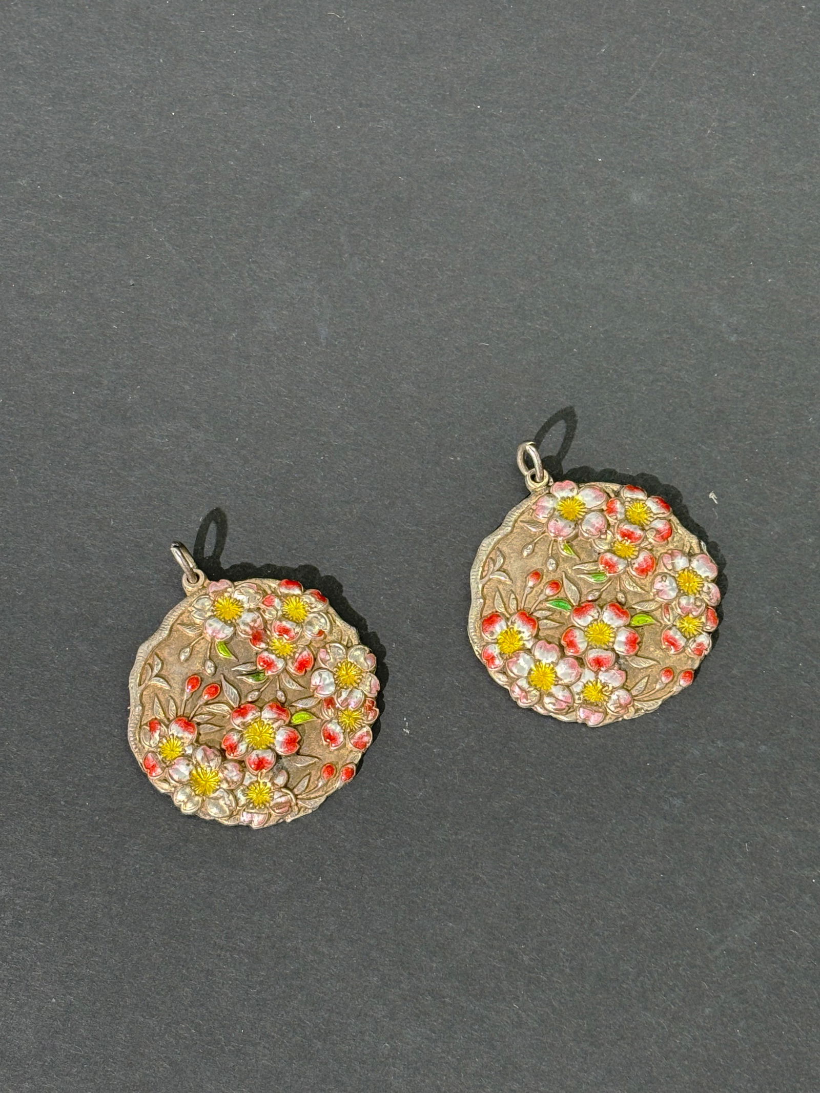 2 Japanese Cherry Blossom Enameled Silver Pendants: 2 Japanese Cherry Blossom Enameled Silver round Pendants with traces of gilding to top, the design in repousse work over flat polished backs each with "jungin" pure silver hallmark with small loop and