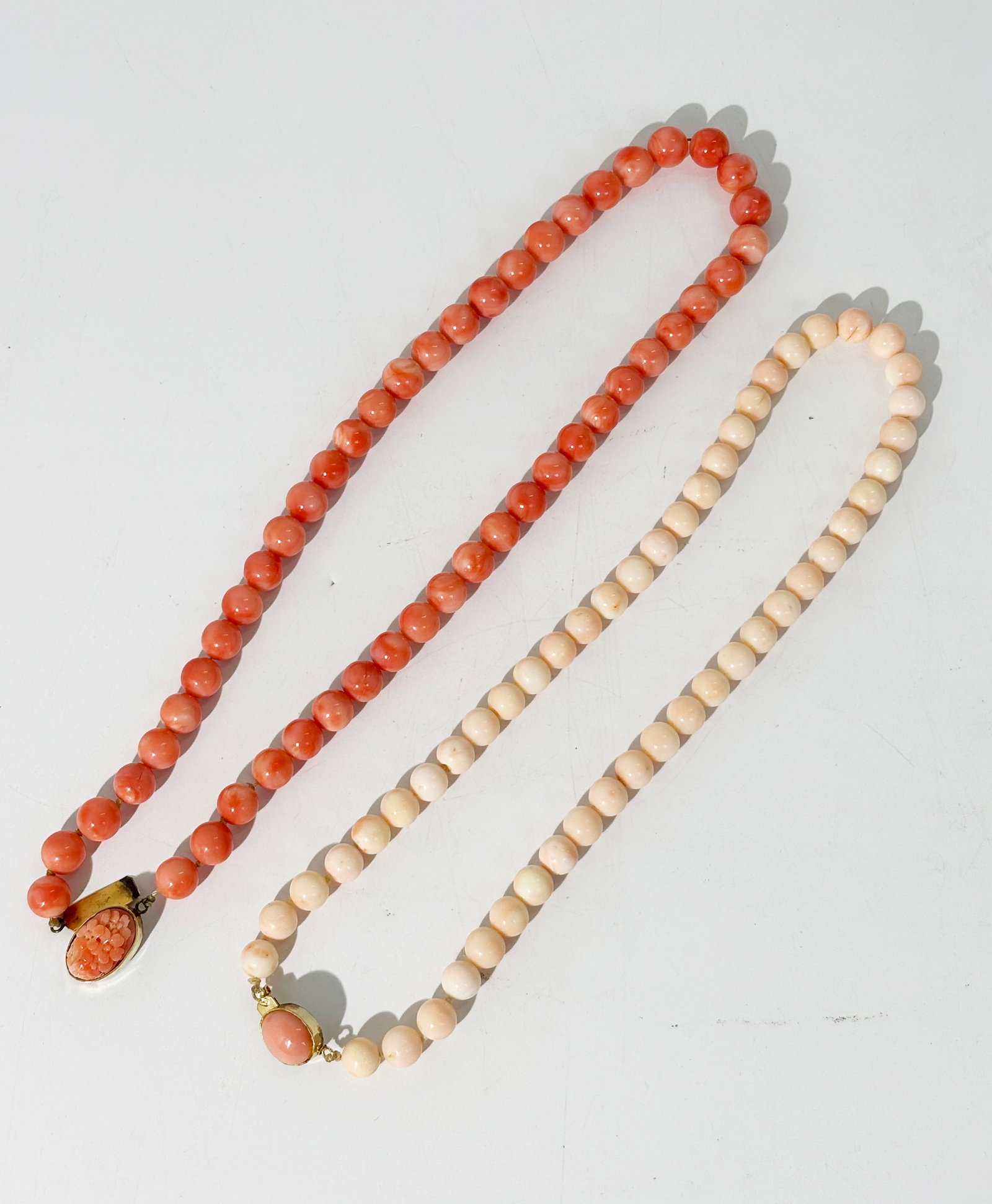 2 Vintage Coral Bead Necklaces: 2 Vintage Coral Bead Necklaces, 1 in Angel Skin with a slightly darker cabochon gilt silver closure, and 1 in darker coral with flower carved coral cabochon in gilt silver closure. Length of darker be