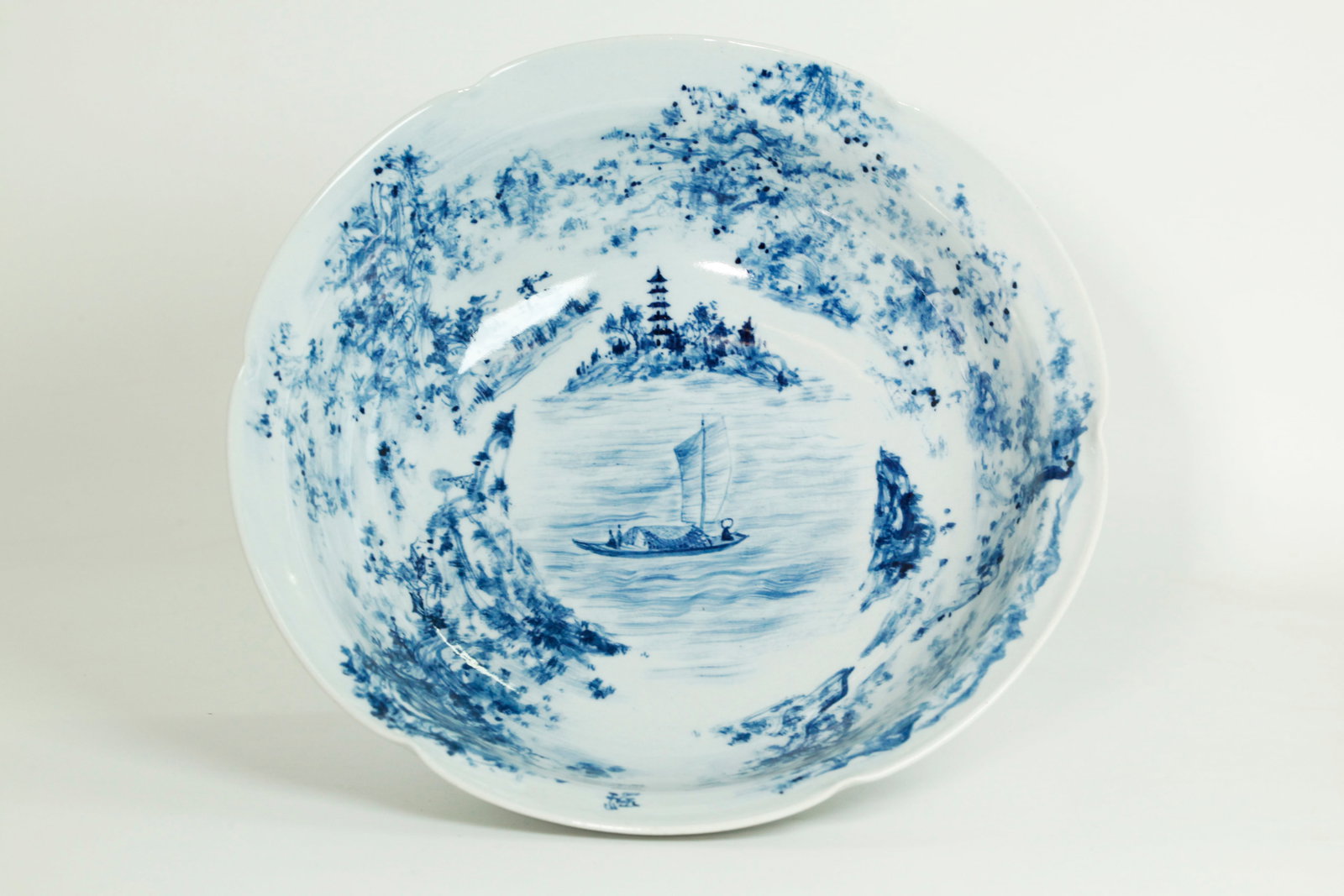Fu Yiyao; Chinese Artist Blue Porcelain Bowl: Fu Yiyao; Chinese Artist painted underglaze Blue Porcelain Bowl with 6 crimps to the outside edge, the inside with a Fisherman's Boat to center viewing landscapes with trees, rocks, mountains, a Pagod