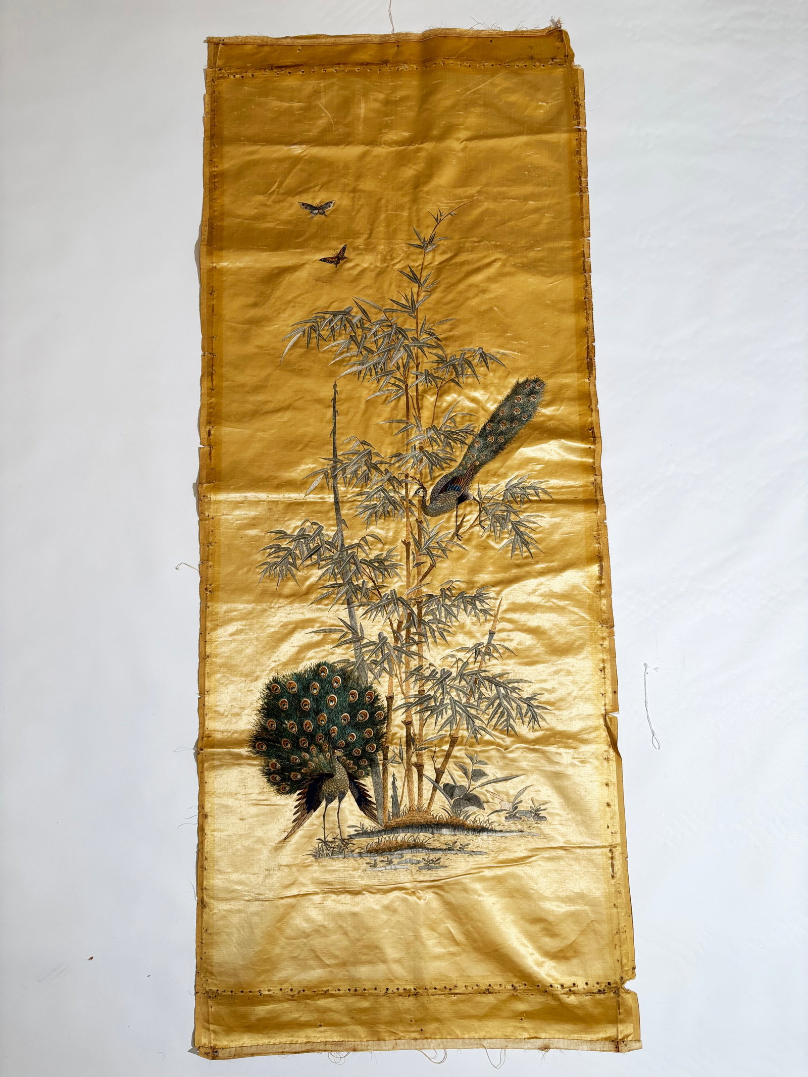 Chinese Qing Dynasty Yellow Satin Peacock Panel: Chinese Qing Dynasty Yellow Satin Panel with selvage edges to both long sides embroidered with a Peacock at a ground pond and a Peahen in Bamboo with 2 small butterflies in the the sky; with fine line