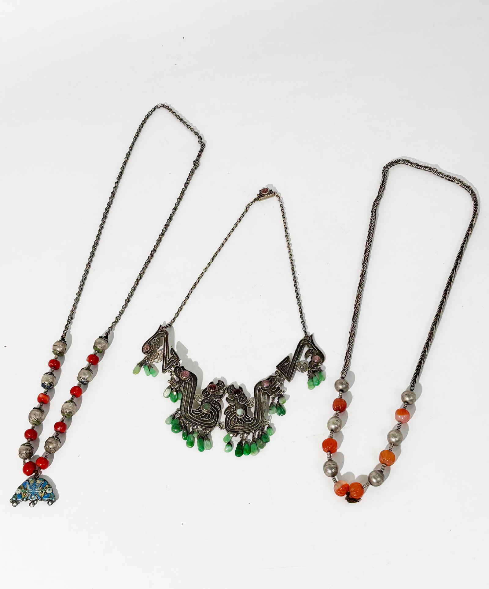 3 Chinese Late Qing Silver Necklaces: 3 Chinese Late Qing Silver Necklaces: a fine chain necklace with confronting archaistic Dragons in wire-work with small tourmaline cabochons in pink and small green jadeite drops forming a fringe belo