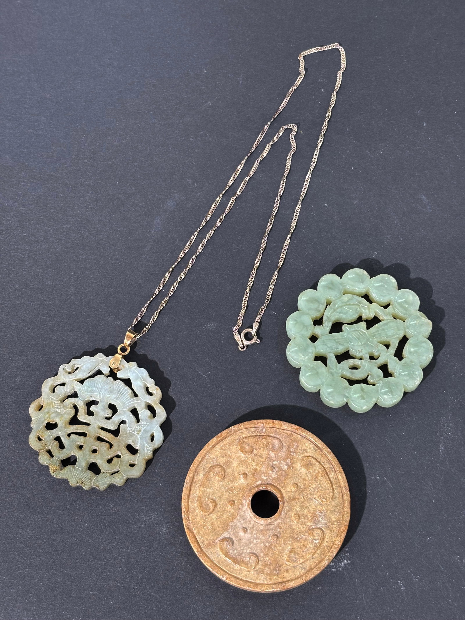 2 Chinese Pierced Jade Pendants; 1 Archaistic Bi: 2 Chinese Pierced Jade Pendants: a Ming Dynasty pale celadon disc carved to both sides and pierced with a flower stem & leaf inside a ball border and a Qing Dynasty pale greenish white jade or jadeite