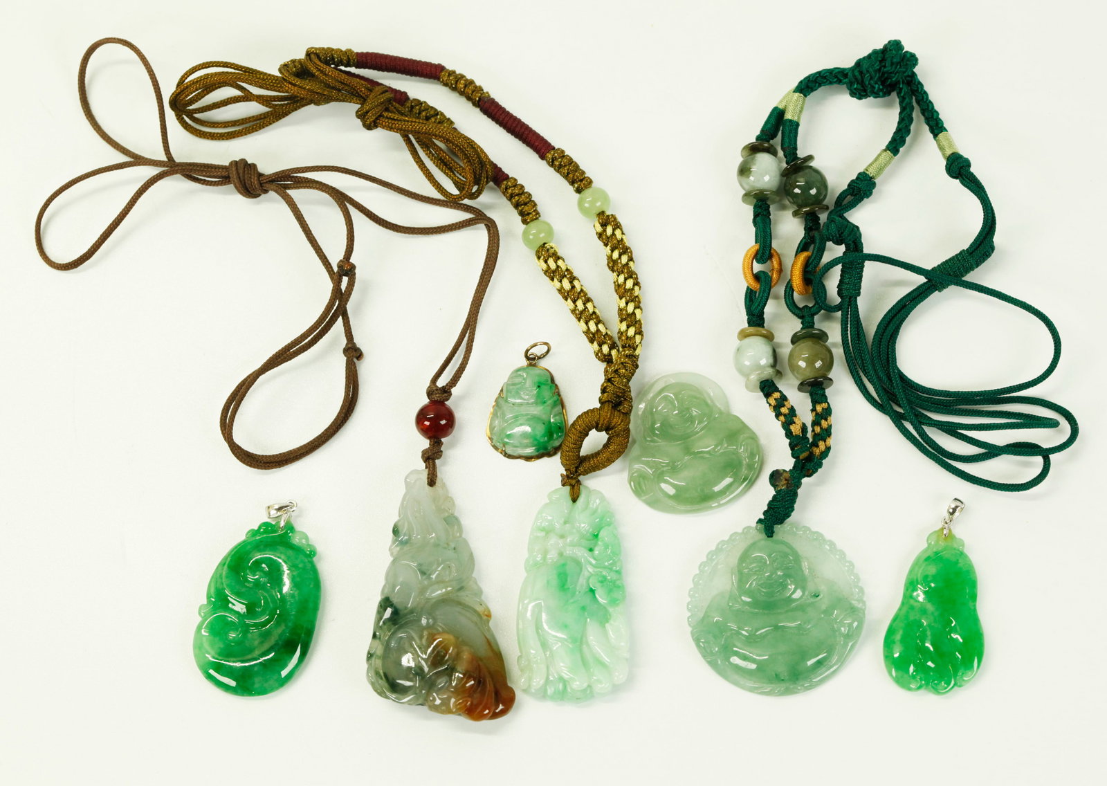 7 Good Chinese Translucent Jadeite Pendants: 7 Good Chinese Translucent Jadeite Pendants: 2 in rich green with white gold hangers marked "750," 3 Budai Buddhas, 2 in pale celadon "Icy" Jadeite and 1 with macrame cord with extra beads, the smalle