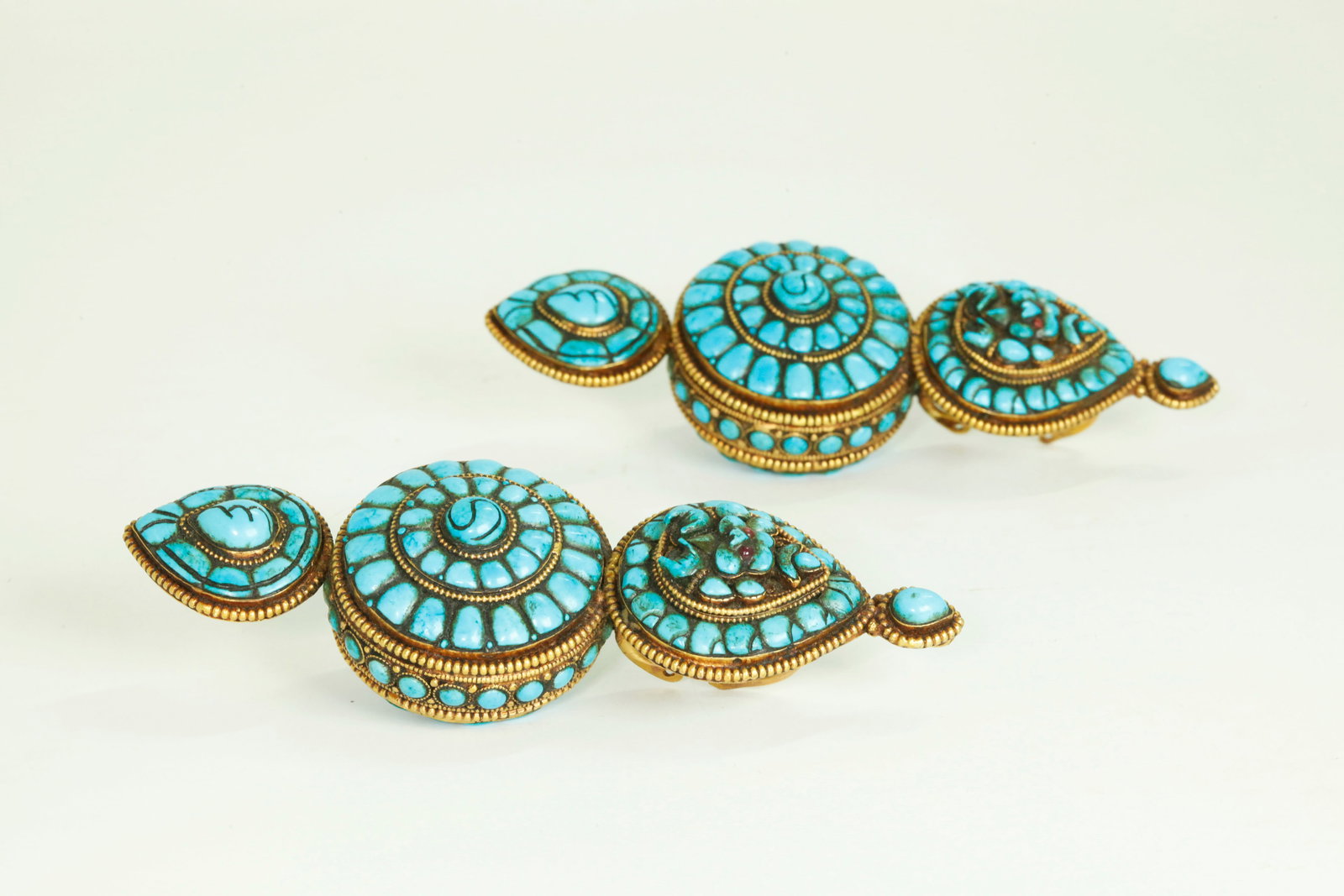Pr Tibetan Vintage Turquoise Akor Garuda Pendants: Pair Tibetan Vintage Turquoise Akor Garuda Ear Pendants in 3 parts ending in Lotus Buds at bases, the turquoise set in gilt metal with hooks to reverse. Height 5 3/4 inches X width 2 inches. NOTE: Wor