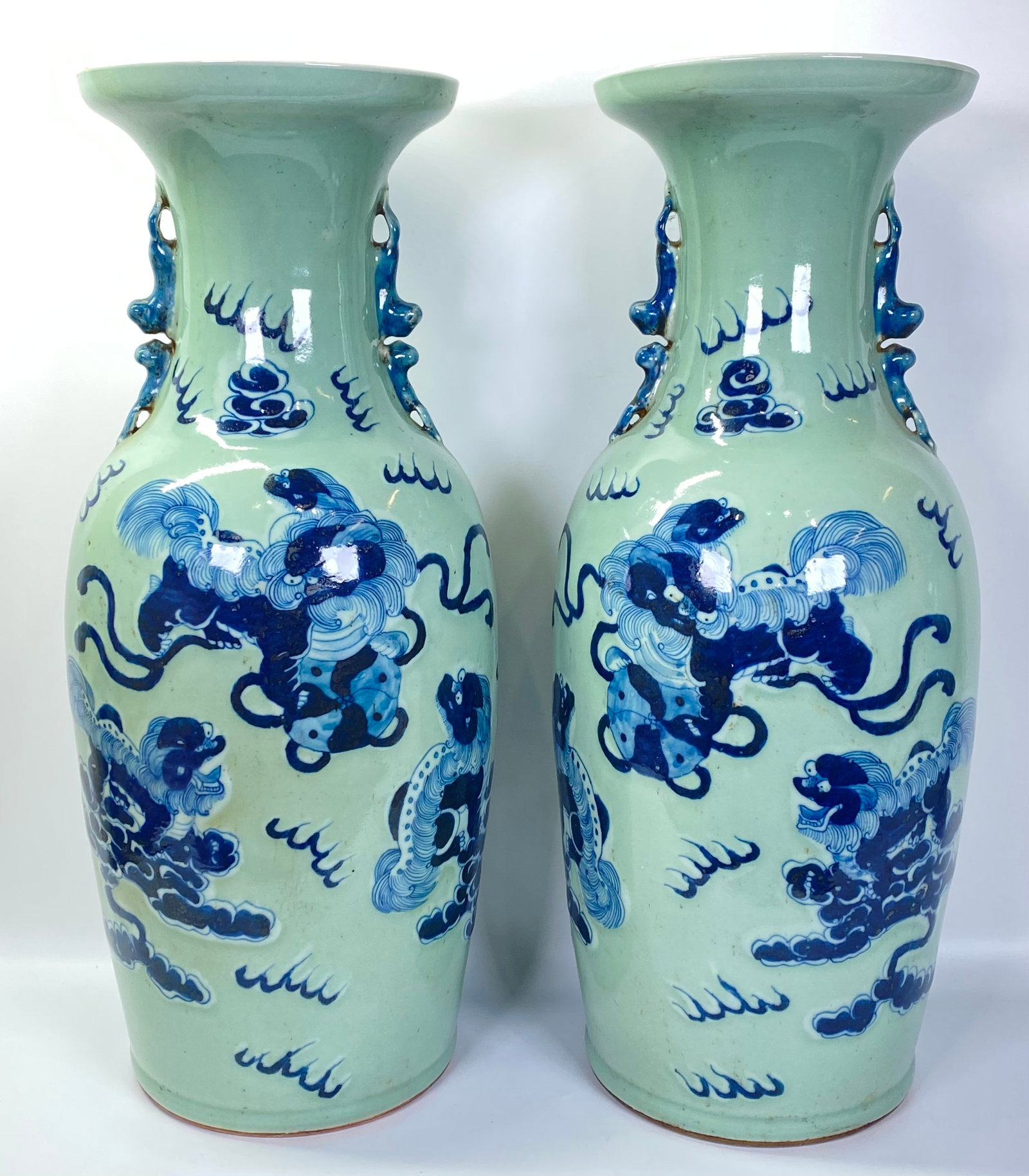 Lg Pair Chinese Blue White Celadon Vases: Large Mirror Pair Chinese Blue Fu Dog Vases the 3 Dogs with Brocade Balls & Ribbons in clouds and flames on White slip over a Celadon glaze, each neck with blue applied double Fu Dog handles to neck.