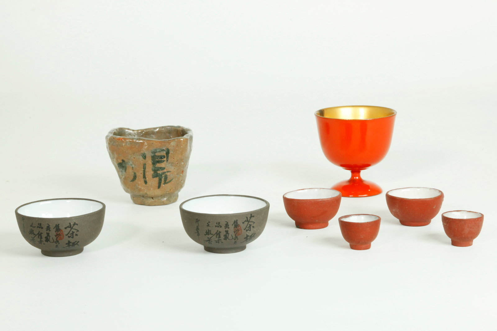 6 Chinese Mini Yixing Zisha EnamelCups 2 Japanese: 3 Pairs of Chinese Miniature Yixing Zisha Cups each with white enamel to inside, the large pair with black calligraphy & 2 red seals to outside, the smallest pair with white enamel inside foot ring; t