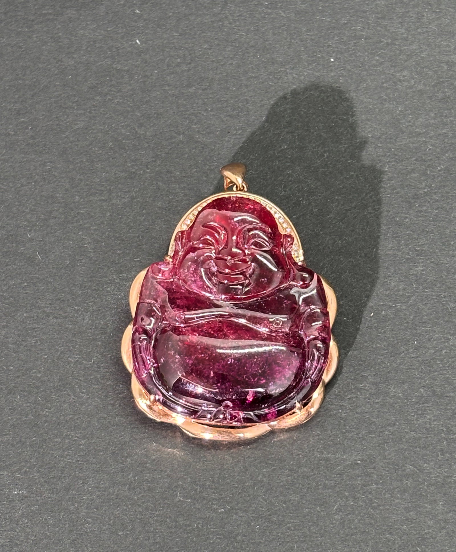 Chinese Dark Pink Tourmaline Buddha & Rose Gold: Chinese Dark Pink Tourmaline Budai Buddha prong set in a Rose Gold open back pendant frame with a row of tiny diamonds around the Buddha's head. Total weight 15.2 grams. Height of pendant 1 5/8 inches