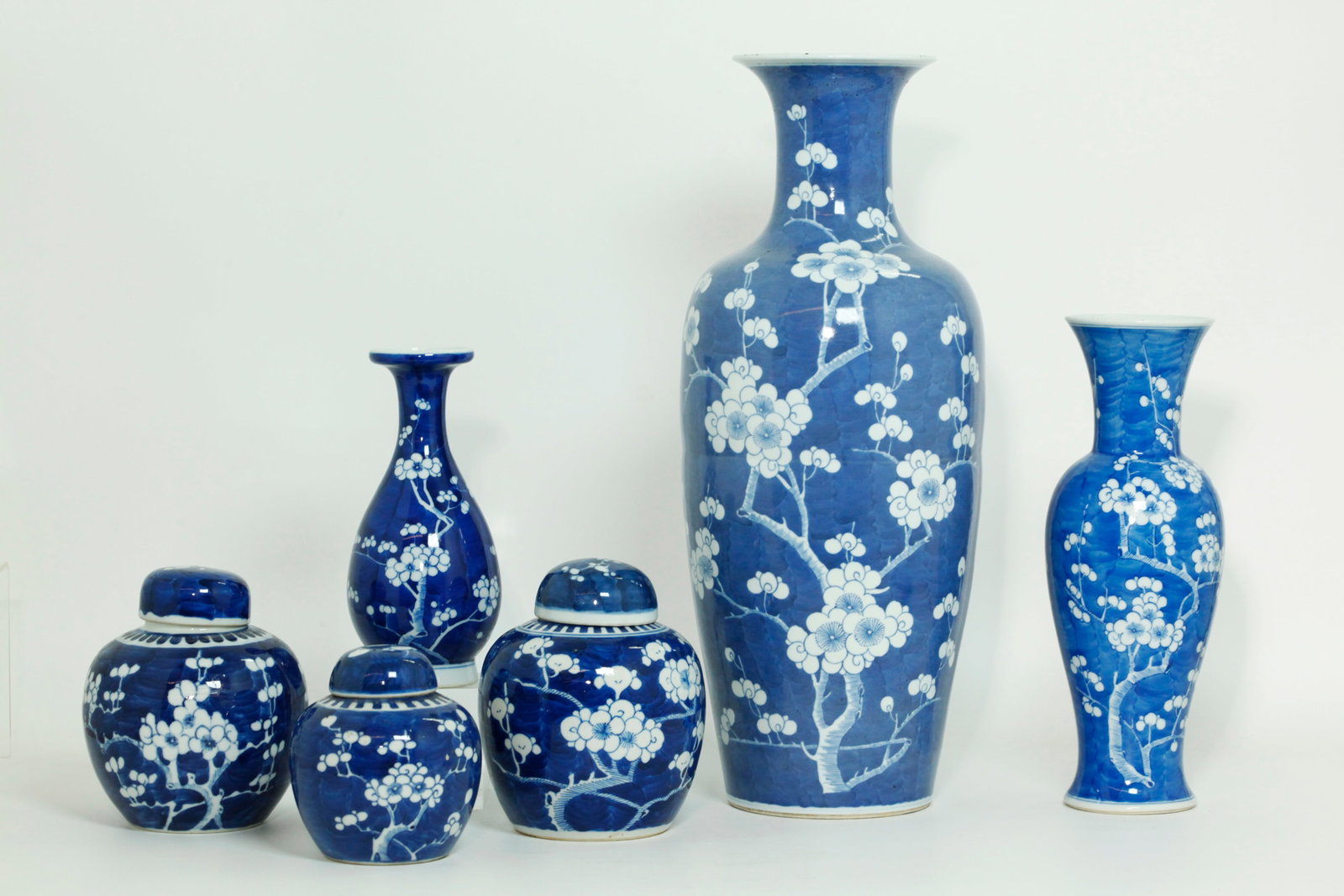 6 Chinese Late Qing Blue & White Prunus Porcelains: 6 Chinese Late Qing Dynasty Blue & White Prunus or Hawthorn Pattern Porcelains; 3 Vases & 3 Ginger or Tea Jars with covers, each with white flowering prunus branches on a wavy blue ground; the largest