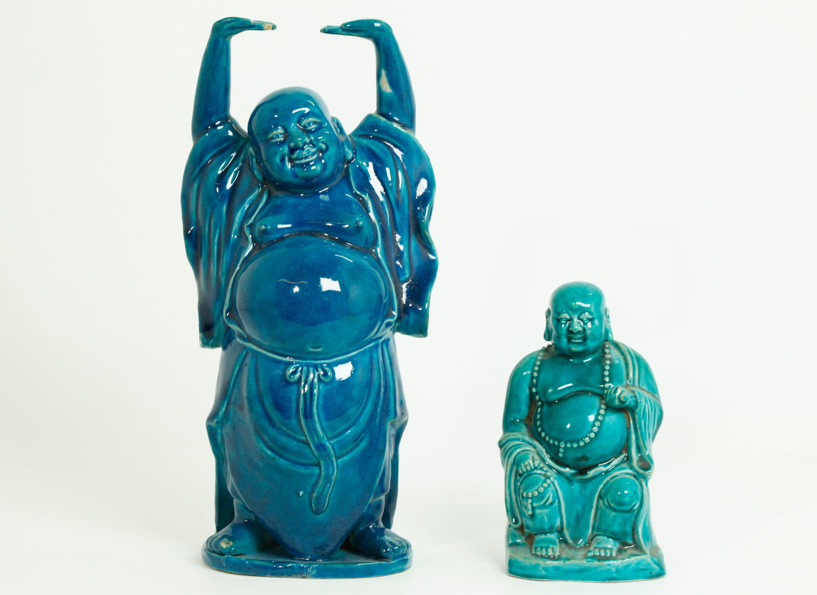 2 Chinese Turquoise Crackle Porcelain Budai Buddha: 2 Chinese Turquoise Crackle glaze on biscuit Porcelain of Budai Buddha, the larger a Laughing Buddha with hands raised in Joy and in a dark turquoise blue on a small flat unglazed base with holes to r
