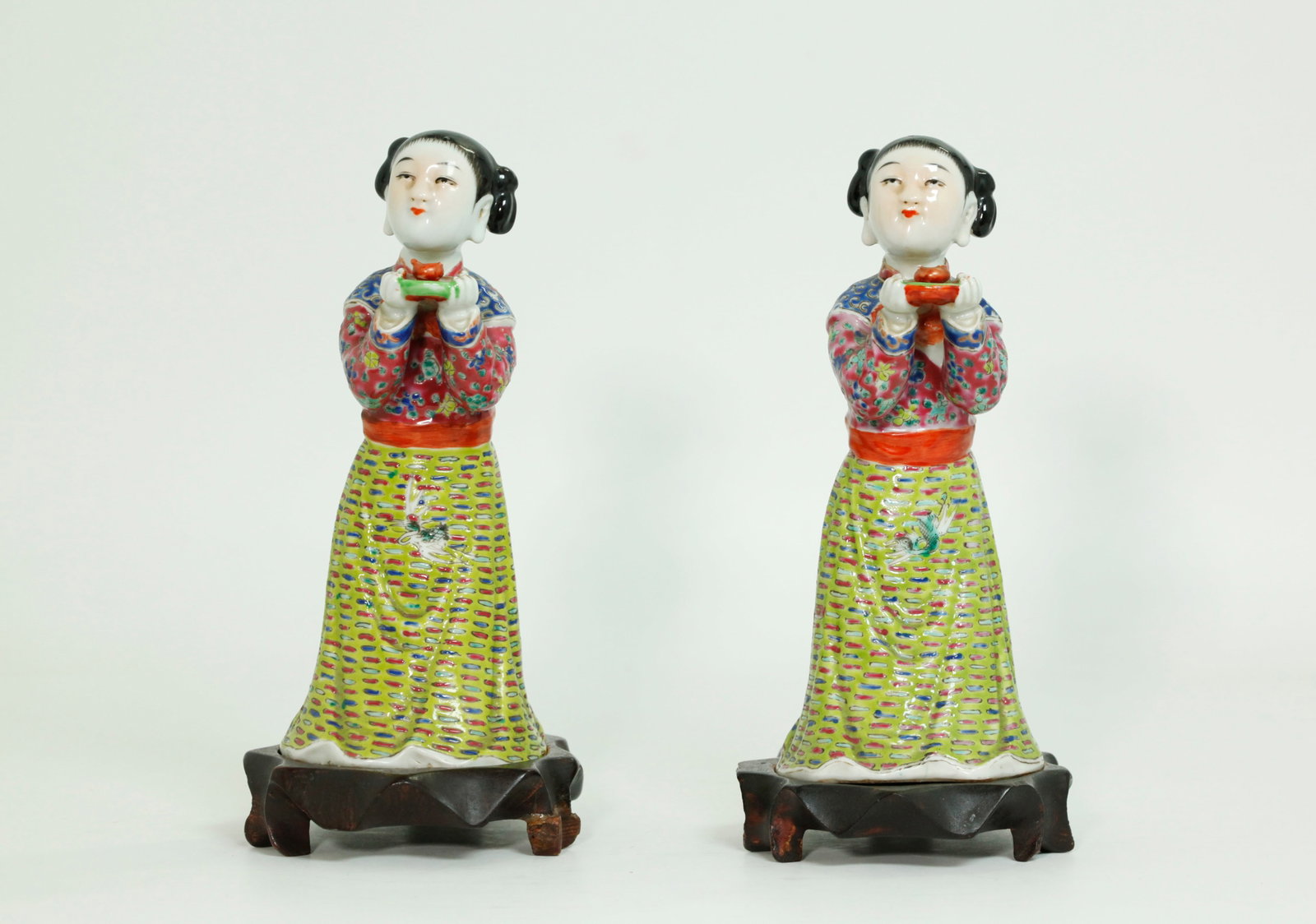 Pr Chinese Enameled Porcelain Court Ladies: Pair Chinese Enameled Porcelain kneeling Court Ladies with "Lily Feet" showing at the back, each holding a small round tray with miniature incense burner and each in matching colorful robes; with flat
