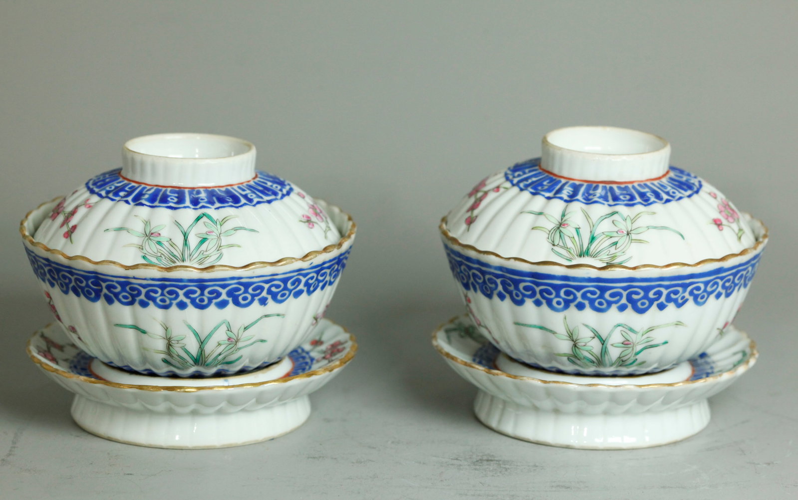 Pr Chinese Porcelain Xianfeng Gaiwan Teabowls: Pair Chinese 19th Century enameled and fluted Porcelain Gaiwan Teabowls, covers and stands with open bottoms, each with wax resist borders of bright blue with sprigs of orchids between flowering branc