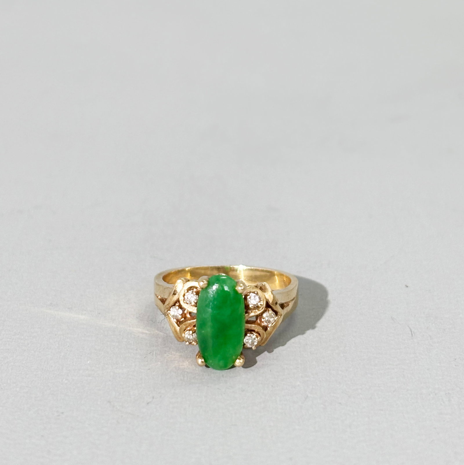 Chinese Emerald-Green Jadeite 14K Yellow Gold Ring: Chinese prong set translucent Emerald-Green oval cabochon Jadeite Yellow Gold Ring marked "14K" and set with 6 prong set diamonds. US ring size 5 1/2. Total weight 4.8 grams.