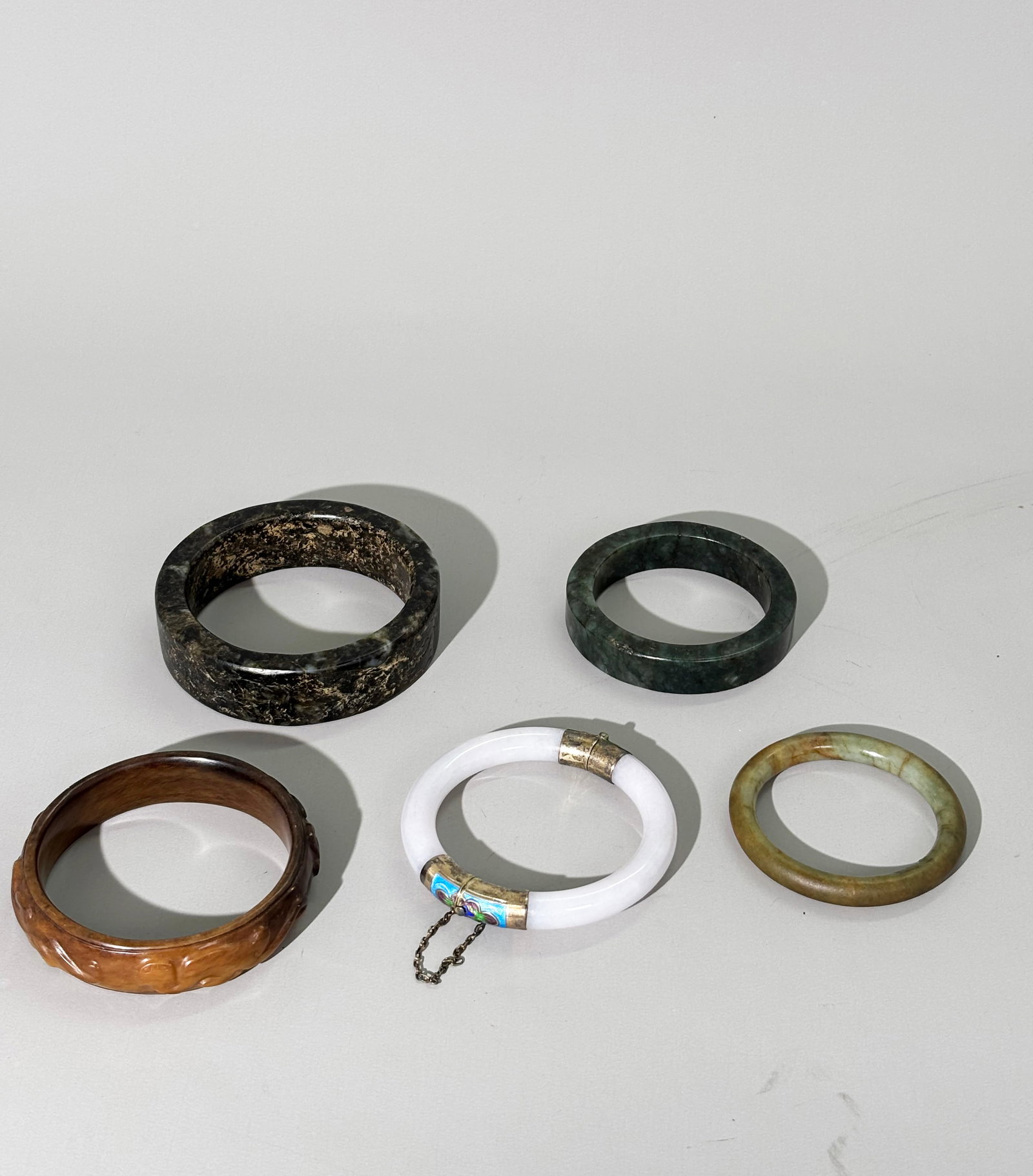 5 Chinese Carved Jade / Jadeite Bangles: 5 Chinese Carved Jade / Jadeite Bangles: The largest, possibly a Ming Dynasty Man's Bangle in mottled black/green jade with 5 shallow carved Chilong Dragons, a green jade bangle, a small celadon bangl
