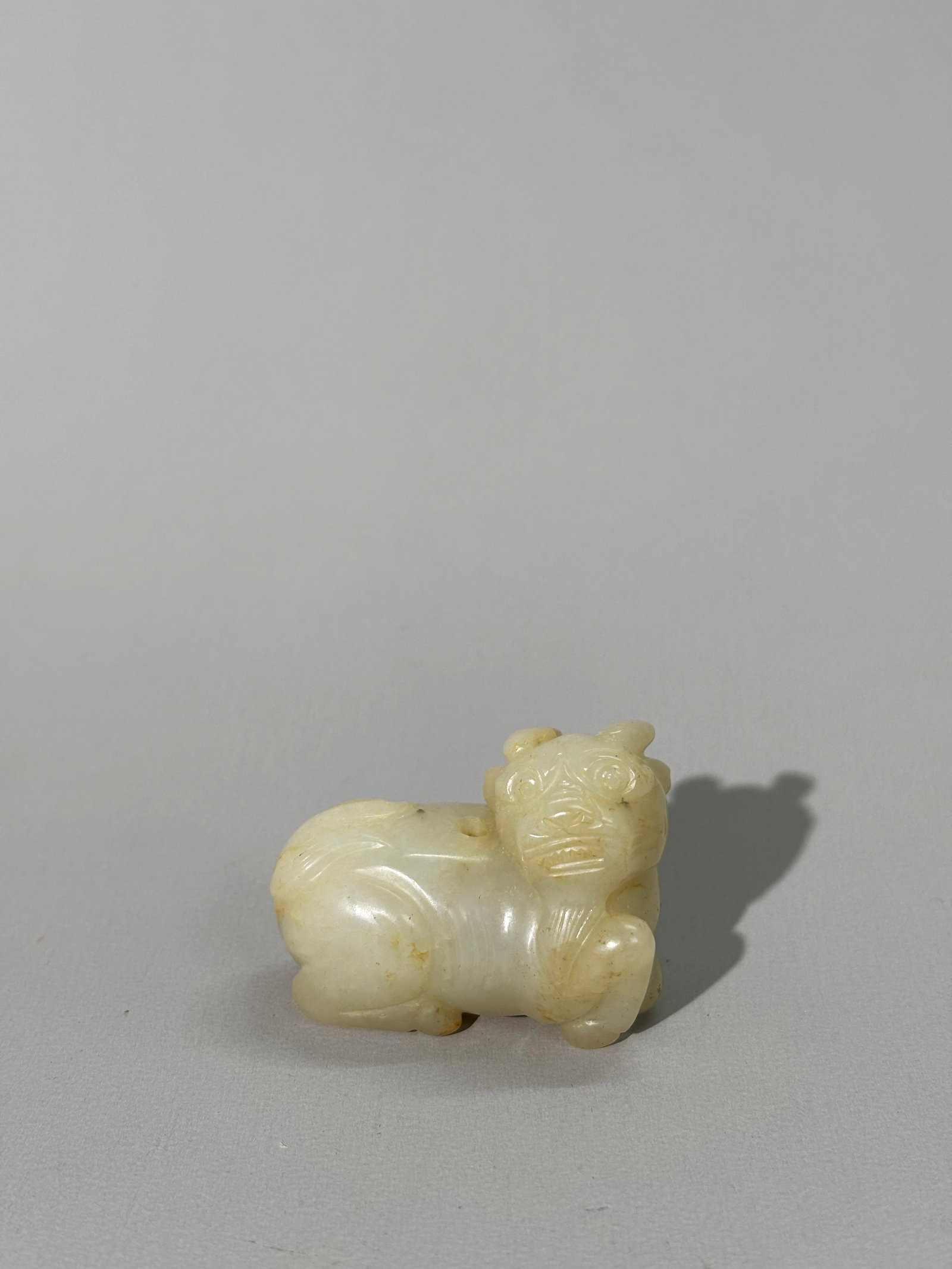 Chinese Pale Celadon Seated 2 Horn Qilin Bead: Chinese Pale Celadon Seated 2 Horn Qilin Bead irregularly drilled vertically through the back for suspension. Height 1 3/8 inches X width 1 7/8 inches.