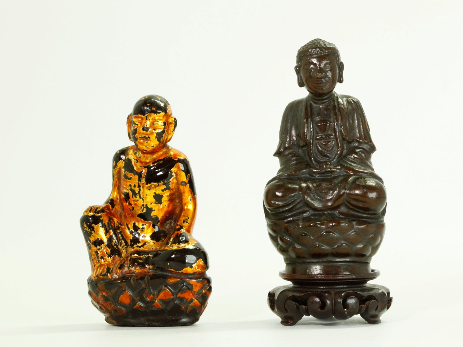 Chinese Bronze Buddha; Lacquered SEA Lohan: Chinese Ming Dynasty to Qing Dynasty Bronze seated Buddha on Lotus Throne now coated in brown lacquer; together with a black & gold Lacquered South East Asian seated Lohan on Lotus Throne; small wood 