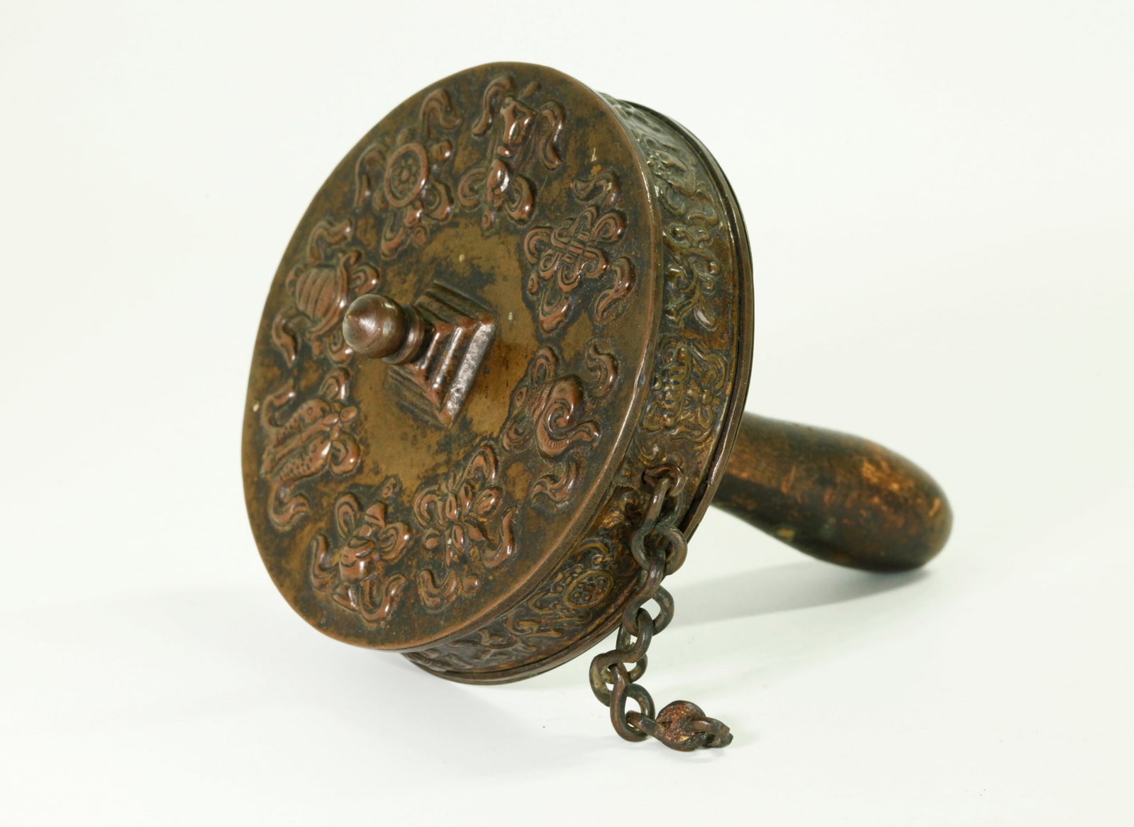 Tibetan Bronze Prayer Wheel; Wood Handle: Tibetan Bronze Prayer Wheel, the top and sides with repousse work each forming a set of the 8 Buddhist Emblems; the Wood Handle attached to a pin through the wheel center forming a small Stupa finial 