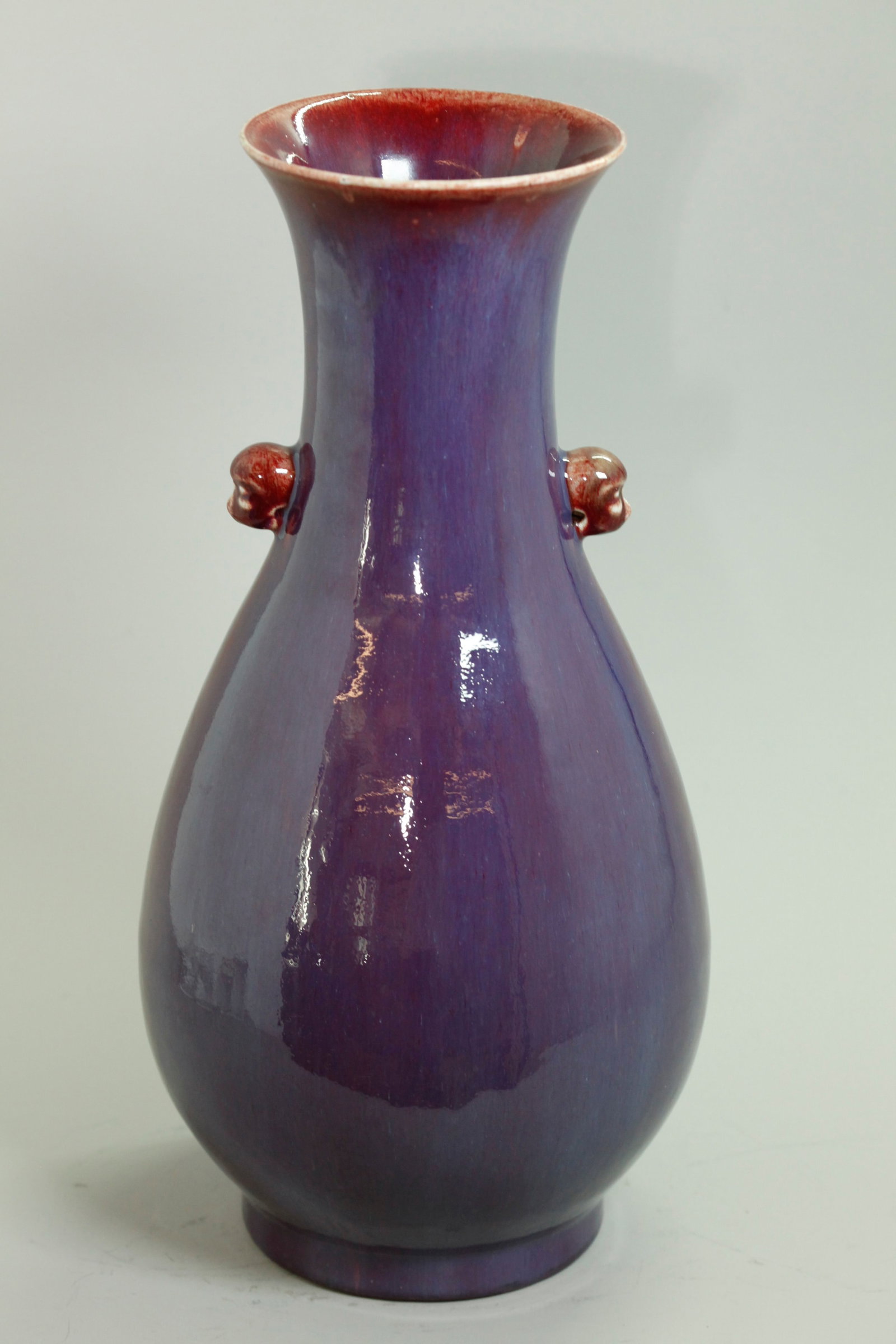 Lg Chinese Underglaze Red & Flambe Porcelain Vase: Large Chinese Qing Dynasty Underglaze Red Crackle Porcelain Vase with animal head handles to the neck, the thick glaze with a layer of flambe purple thinning around the mouth to a mottled pink and wit