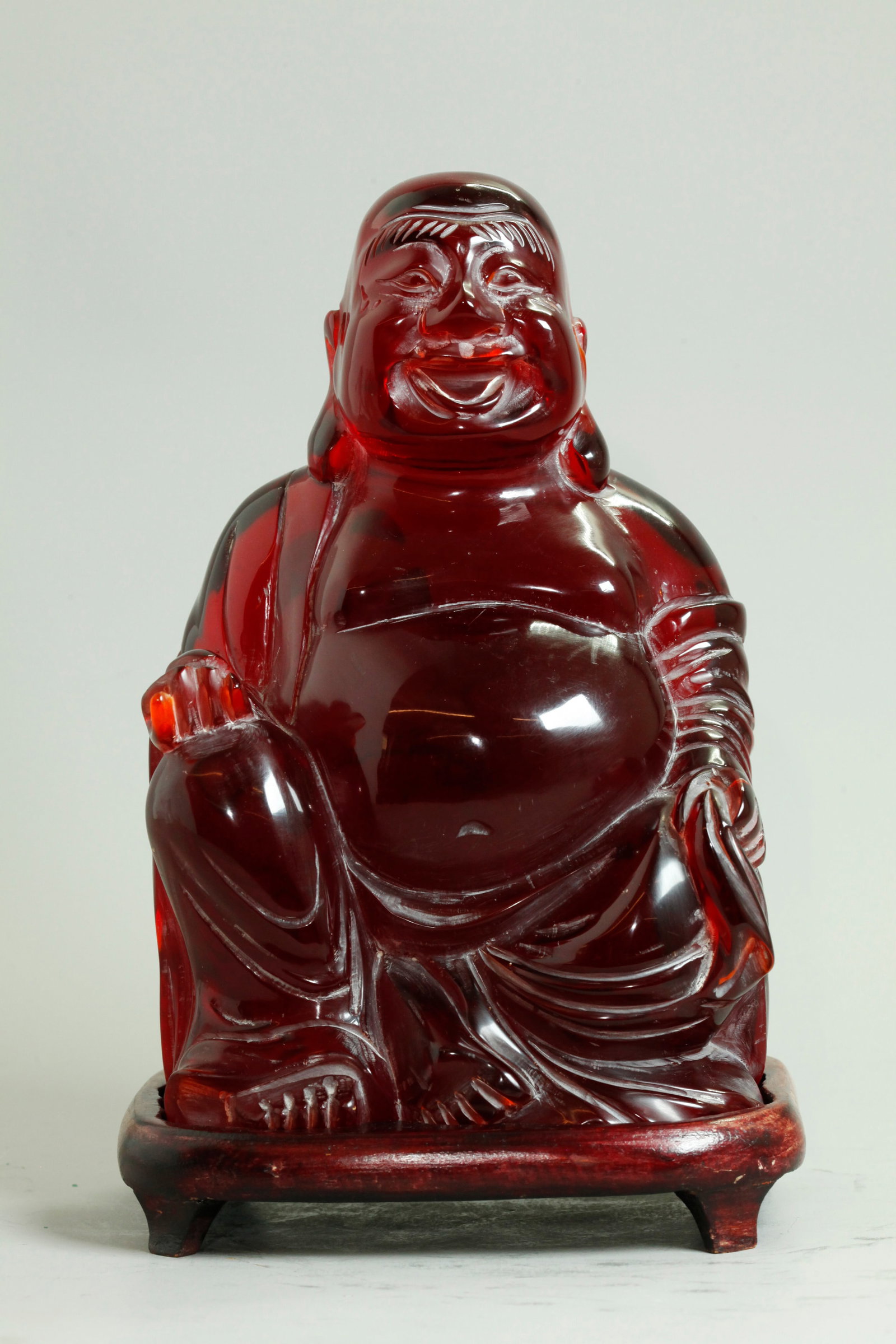 Lg Chinese Cherry Amber Budai Buddha; 2,540G: Large Chinese polished Seated Cherry Amber Budai Buddha holding a Sack and a Pearl of Wisdom; with wood stand. Height 9 1/4 inches X width 6 inches. Weight of Budai Buddha 2,540 grams.