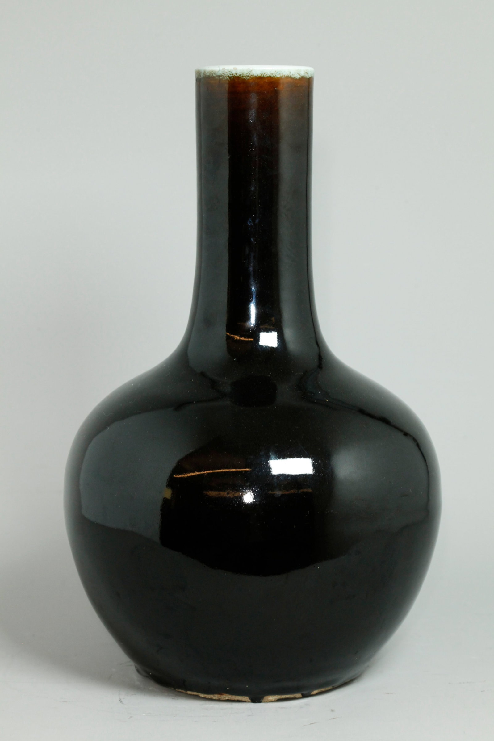 Chinese Qing Black Monochrome Porcelain Vase: Chinese Qing Dynasty Mirror Black Monochrome Porcelain Tianqiuping Vase, the thick glaze thinning to brownish-black at the clear glazed mouth with clear glaze inside and to recessed base; a few black 