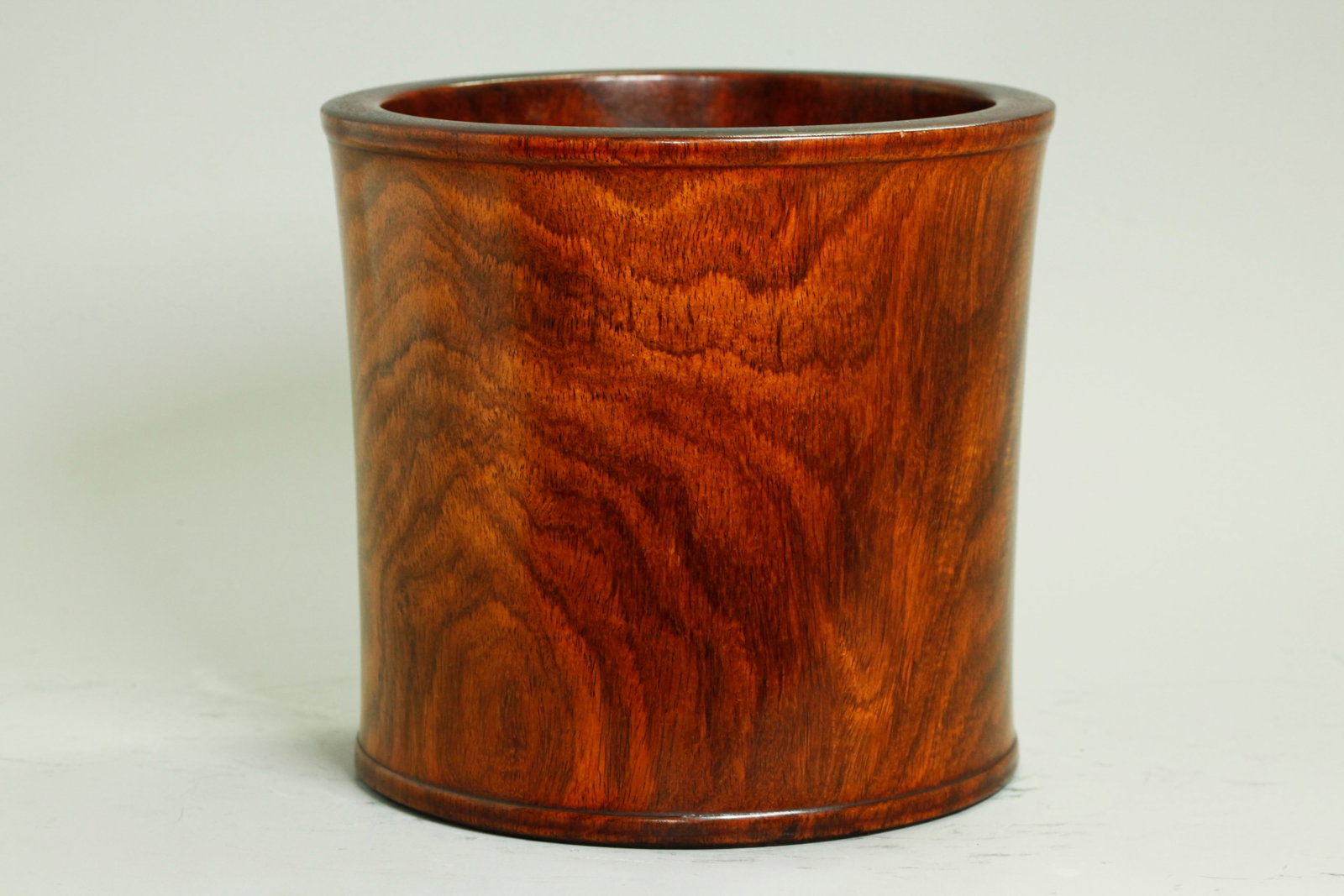 Chinese Huanghuali Bitong Brush Pot: Chinese Huanghuali Bitong Brush Pot in dramatically figured grain with a few small "ghosts" under the polished slightly waisted sides and with a raised bead profile to mouth edge and bottom edge, the 