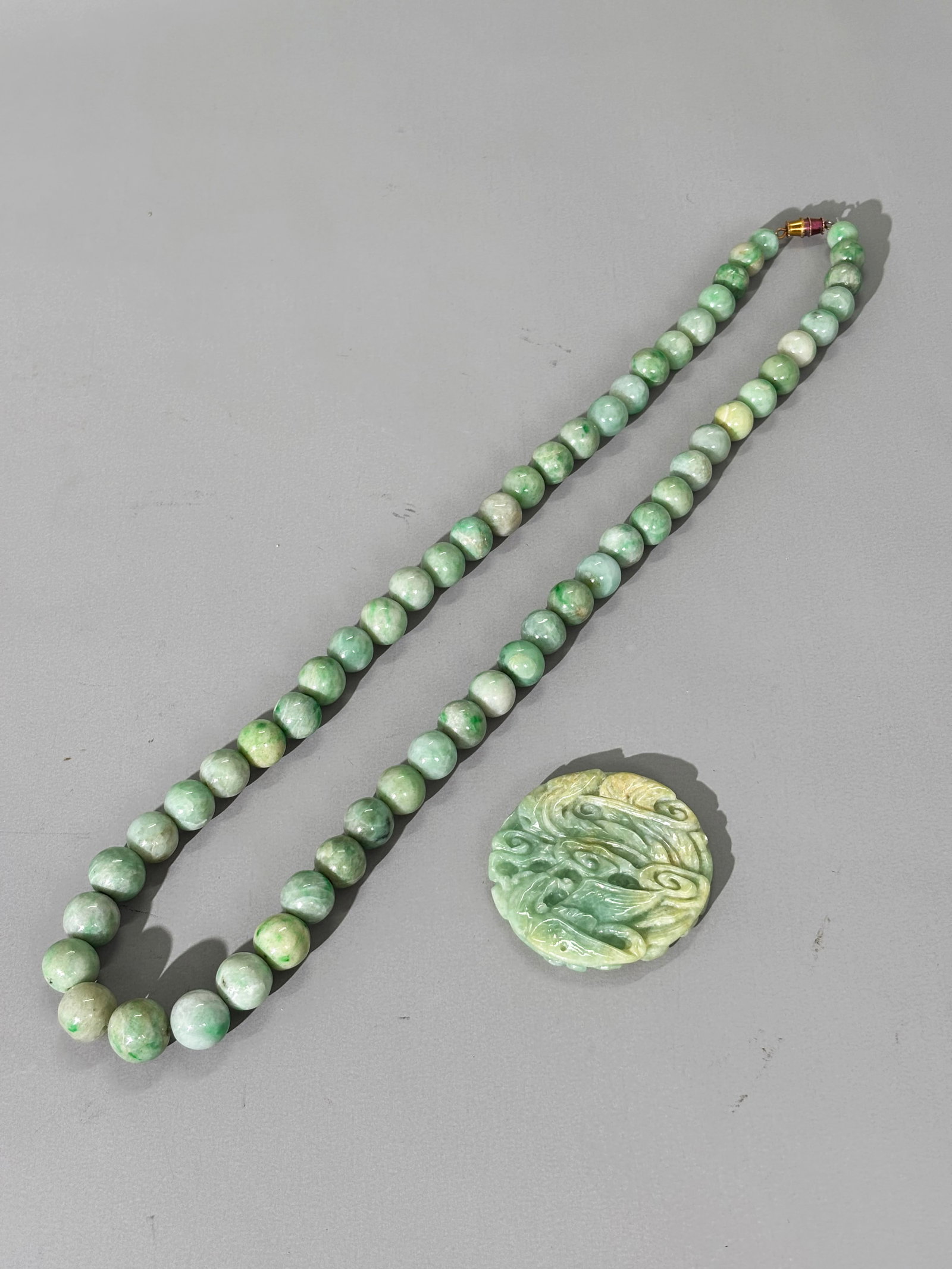 Chinese Vintage 57 Bead Jadeite Necklace & Pendant: Chinese Vintage 57 large drill hole Beads in Jadeite forming a Necklace, the beads in pale green with spots of apple green to dark green & Round Dragon & Flaming Pearl Pendant in pale green to slightl