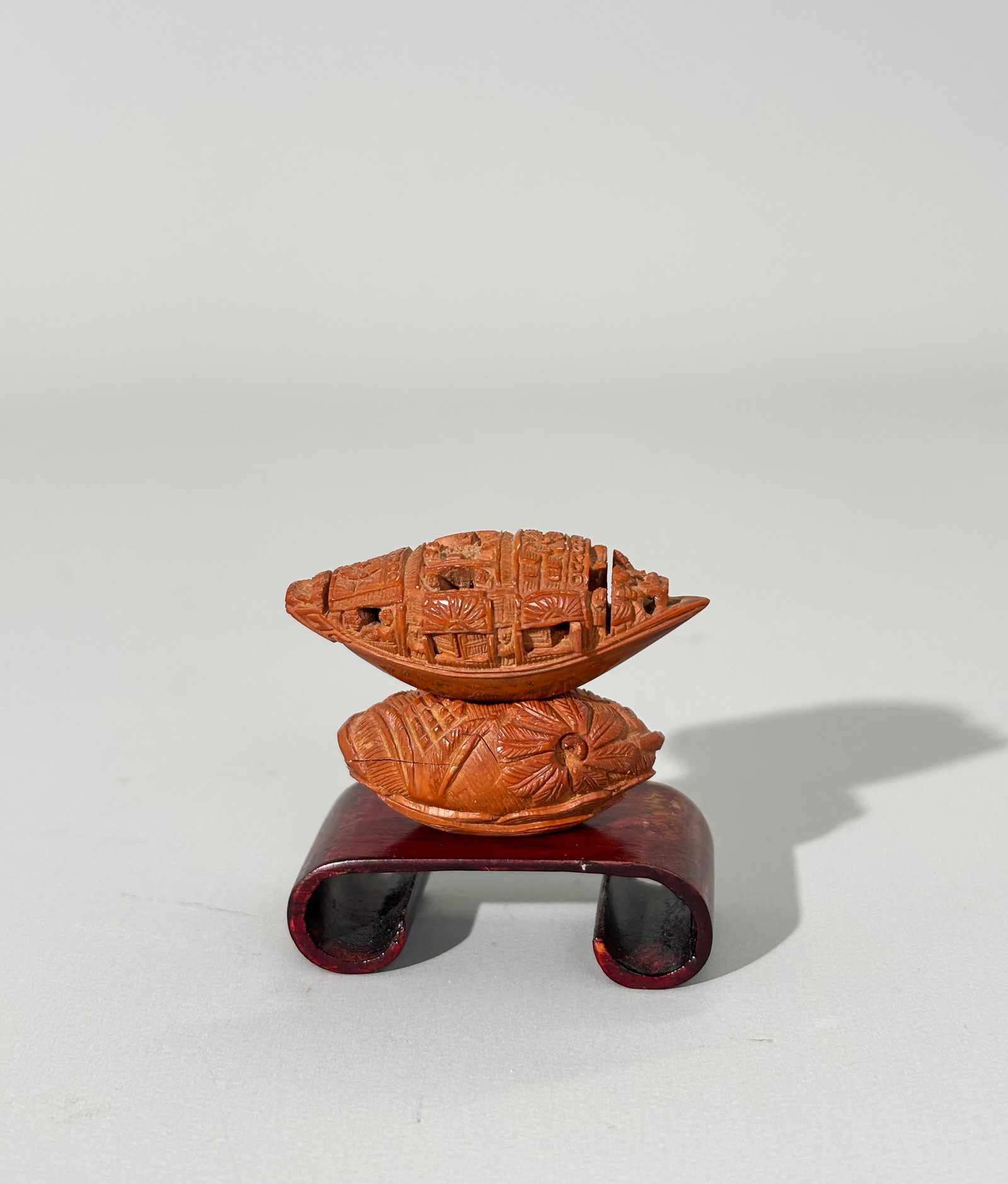 Miniature Chinese Carved Fruit Pit Boat & Stand: Miniature Chinese Carved Fruit Pit Boat with tiny figures outside and an arial view of people looking up from a table to top hatch, 2 sets of operating shutters to each side opening to reveal further 