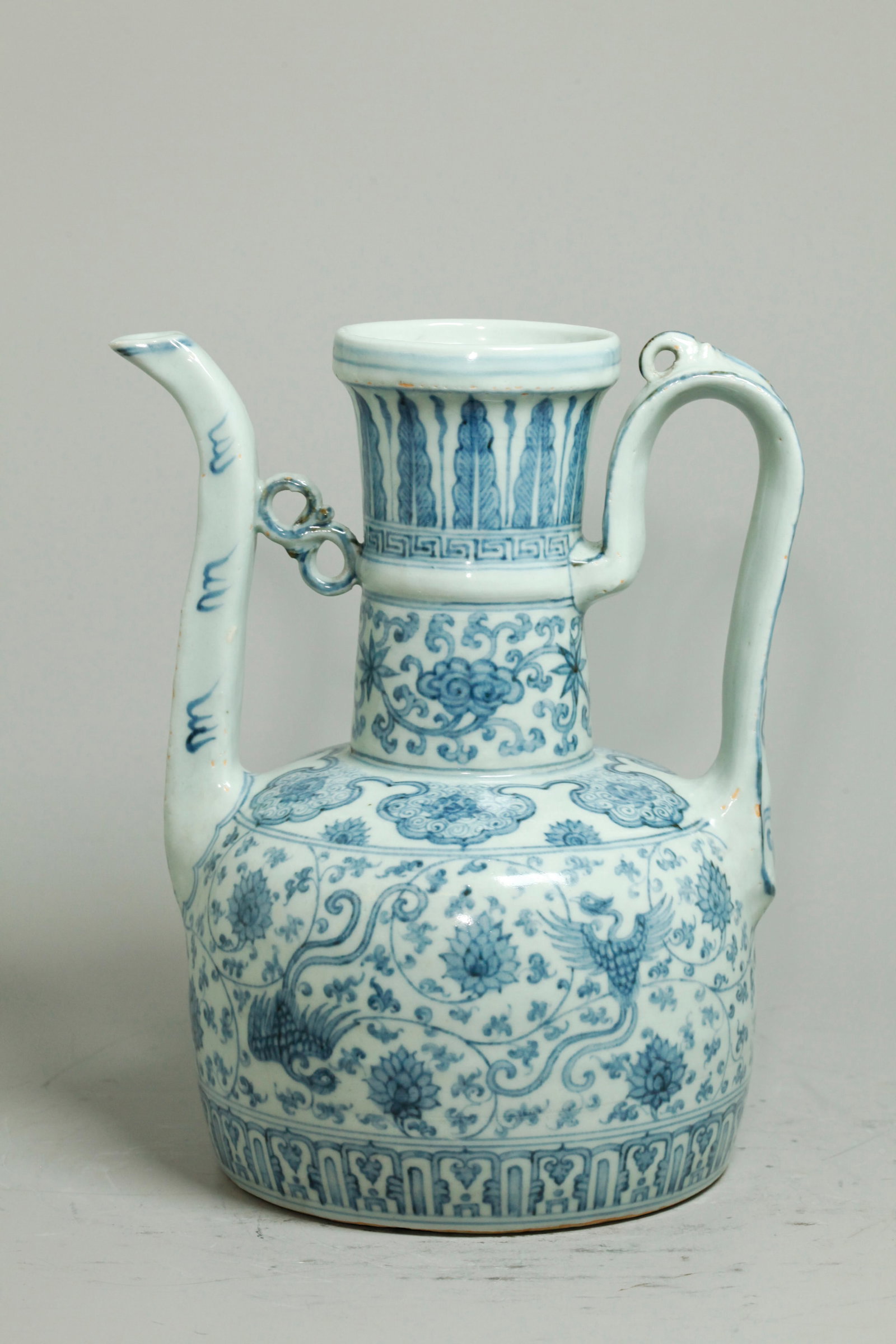 Chinese Blue White Porcelain Ewer Handle & Spout: Large Chinese Blue & White Porcelain Ewer in gray-blue to dark blue, with strap Handle with ring top & Spout with "S" curl brace; the flat base unglazed. Height 10 1/4 inches X handle to sprout 8 1/8 