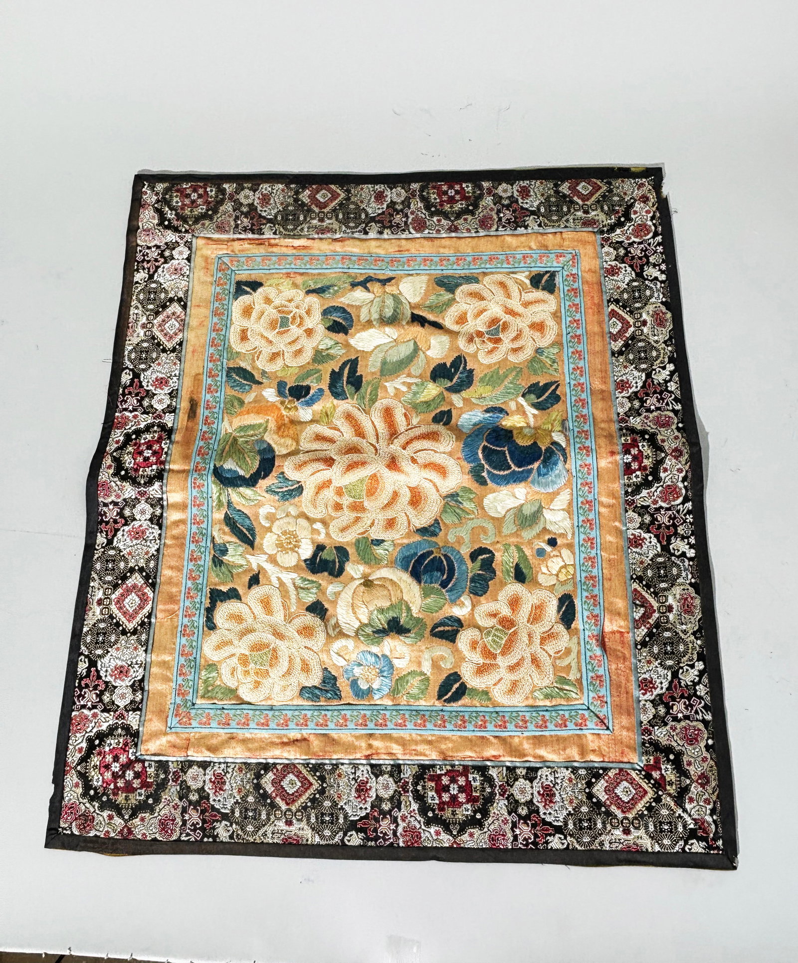 Chinese Qing Silk Embroidered Skirt Panel: Chinese Qing Dynasty Silk Embroidered Skirt Panel with leaves, flowers and melons in colored satin stitch on a pale apricot ground with Peonies to center and 4 corners in Peking Knot embroidery; ribbo
