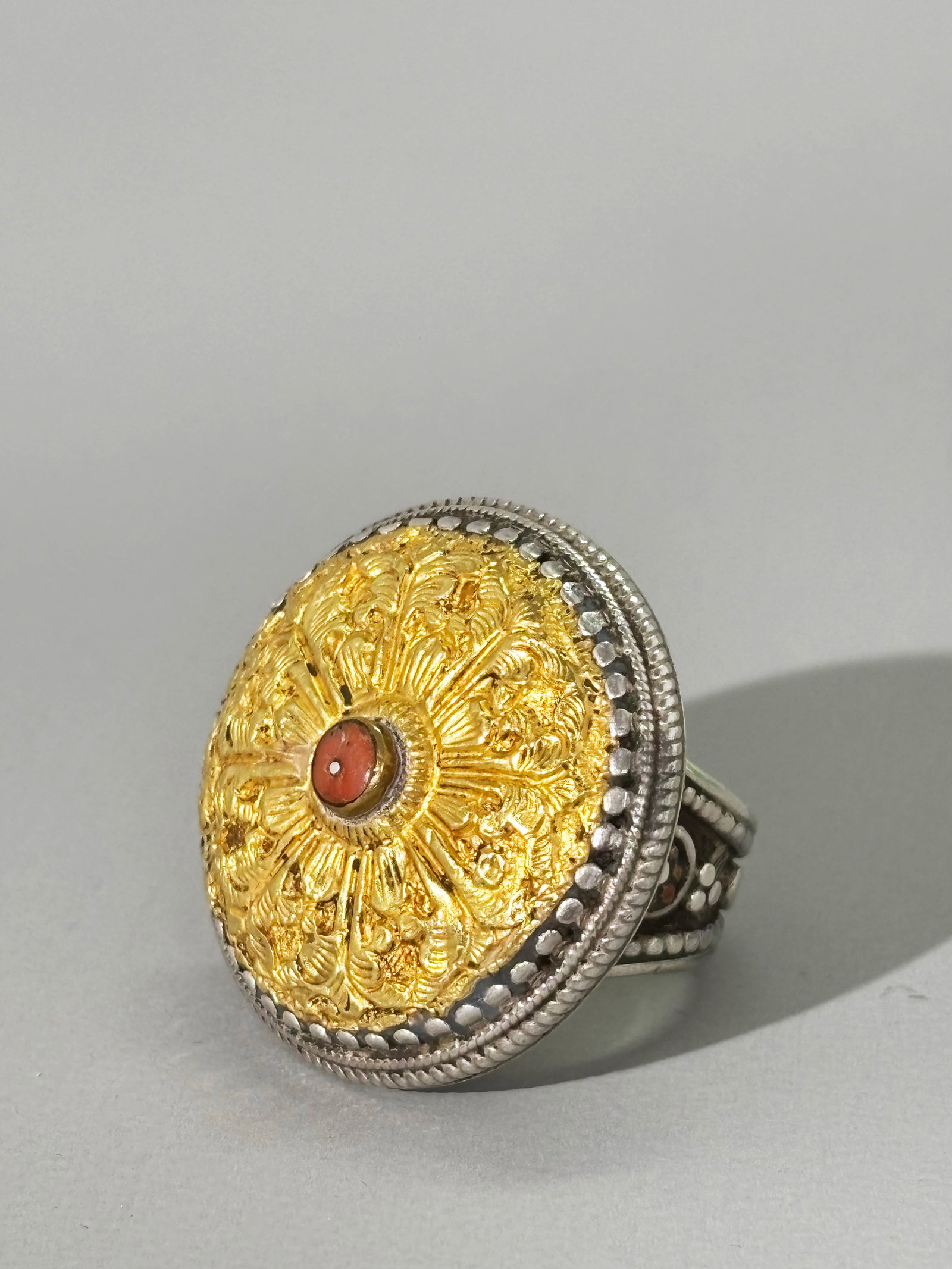Tibetan Coral High Karat Gold & Silver Canopy Ring: Tibetan incised High Karat Gold foil & Silver dome "Canopy" Ring with a small coral bead inset to gold center,2 tiny rosettes of polished copper wire to band decoration under the top; the inside of ba