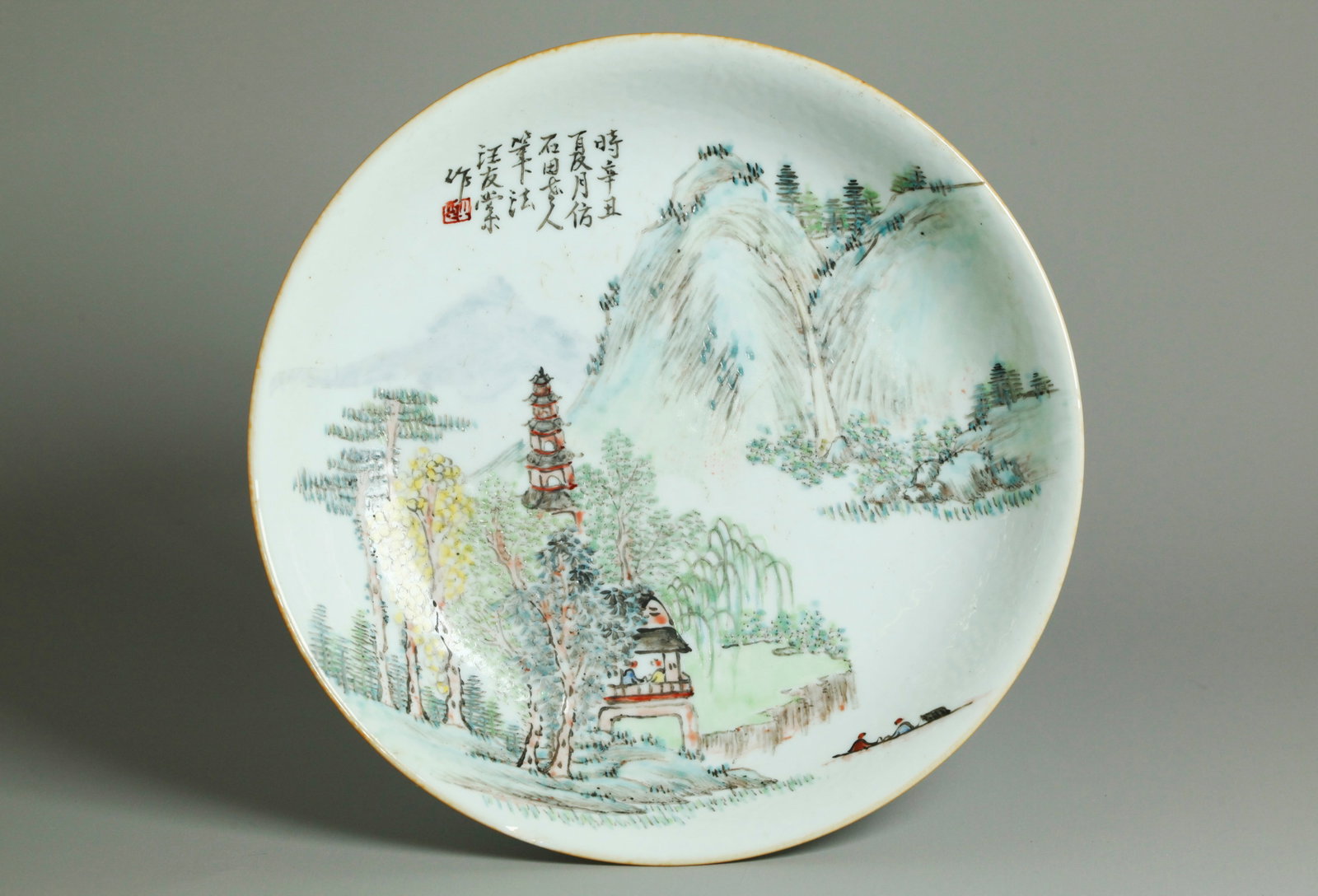 Chinese Artist Enameled Porcelain Landscape Plate: Chinese Artist Enameled Porcelain Landscape Plate with 2 Scholars in a Viewing Pavilion and a Pagoda at Mountain Waterfall with 2 further figures in a boat; with calligraphy inscription and small red 