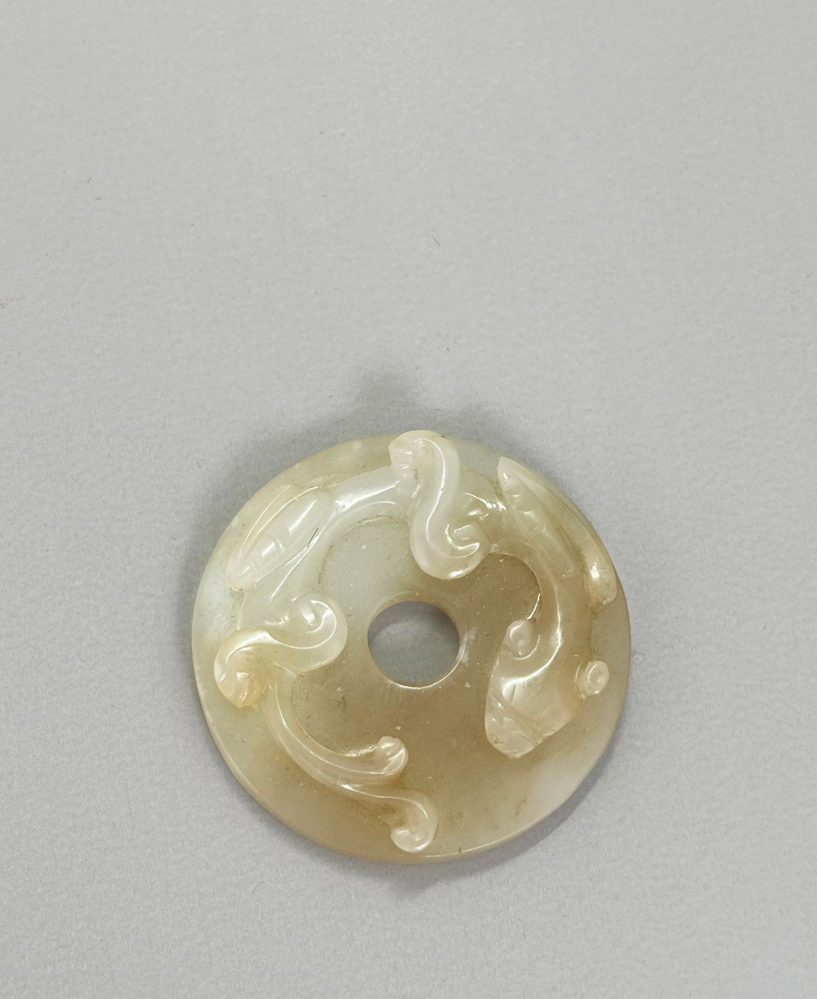 Sm Chinese Pale Celadon Jade Chilong Bi Pendant: Small Chinese Pale Celadon to light brown Bi Ring Pendant carved and polished with a Chilong Dragon to top surface, the flat reverse with 4 "C" curls. Height 1/4 inches X diameter 1 3/4 inches.