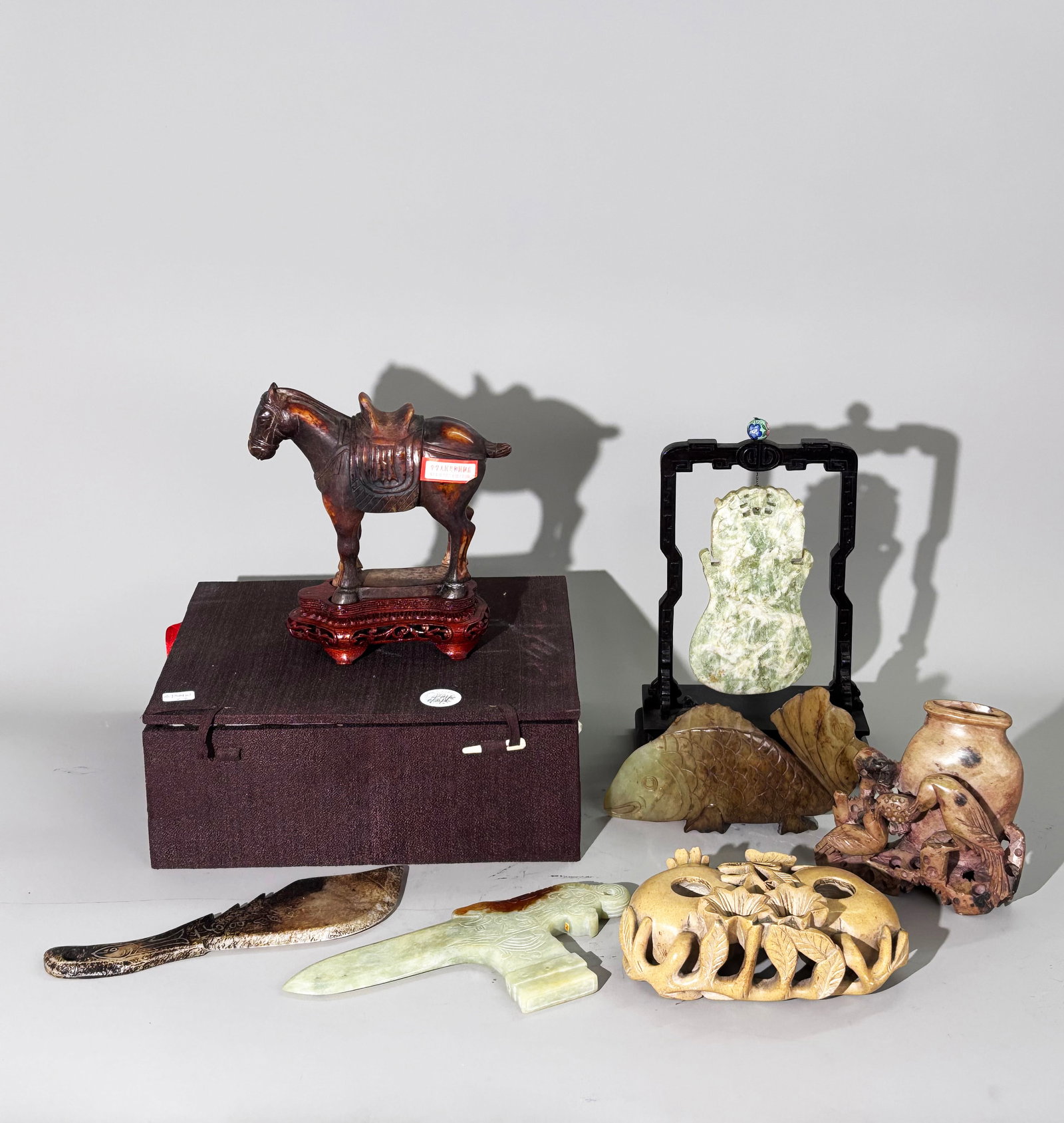 7 Chinese Jade Or Hard Stone Carvings: 7 Chinese Jade Or Hard Stone And Soap Stone Carvings: a Tang-Type standing Horse in russet coloring over pale celadon hard stone with polished flat base, wood stand and custom storage box; a large han