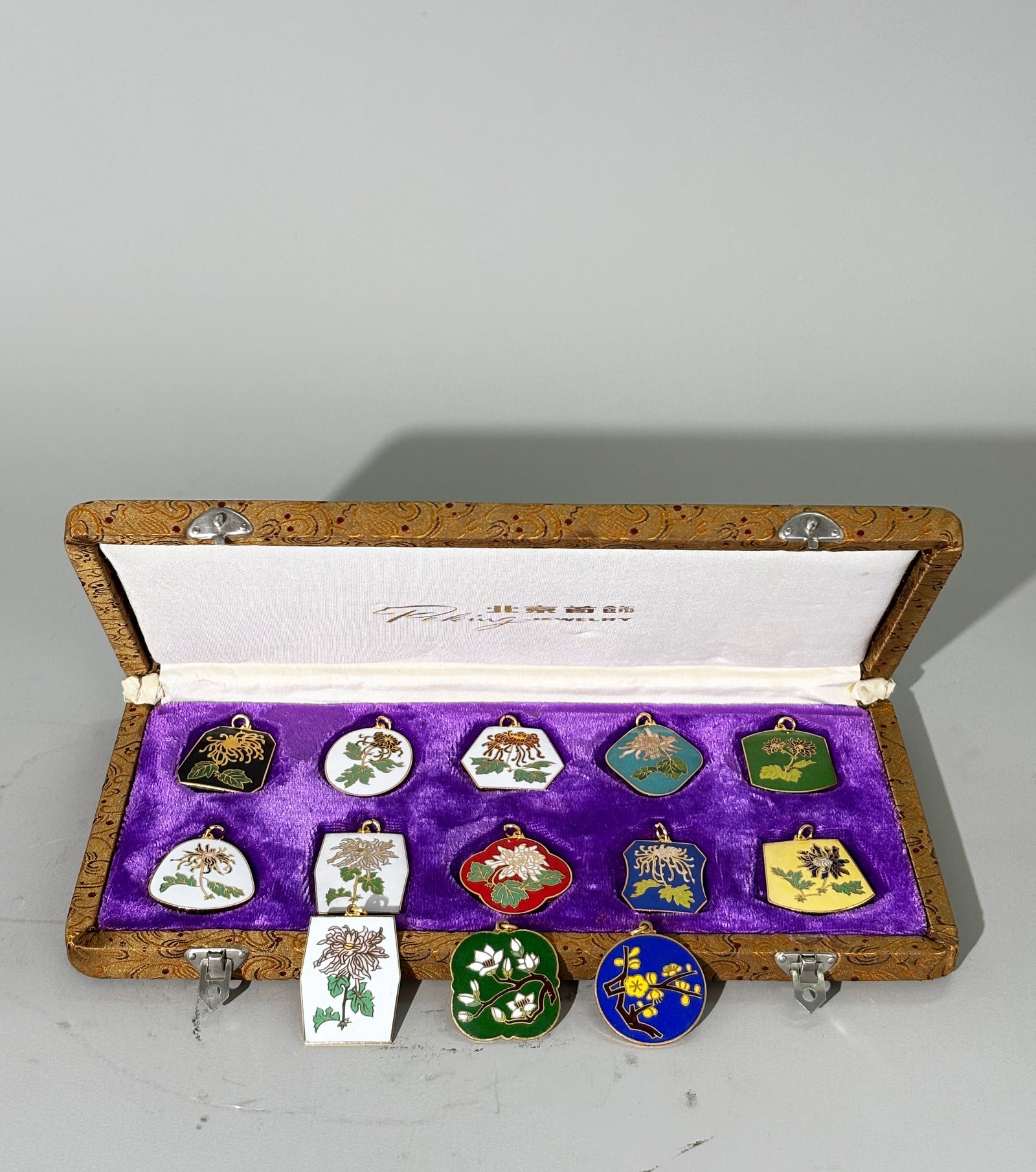 13 Chinese Vintage Champleve Enameled Pendants: 13 Chinese Vintage Champleve Enameled Pendants in gilt copper alloy each stamped with gilt "brocade" patterns to reverse , 11 fronts with different Chrysanthemums on colored enamel grounds with 1 dupl