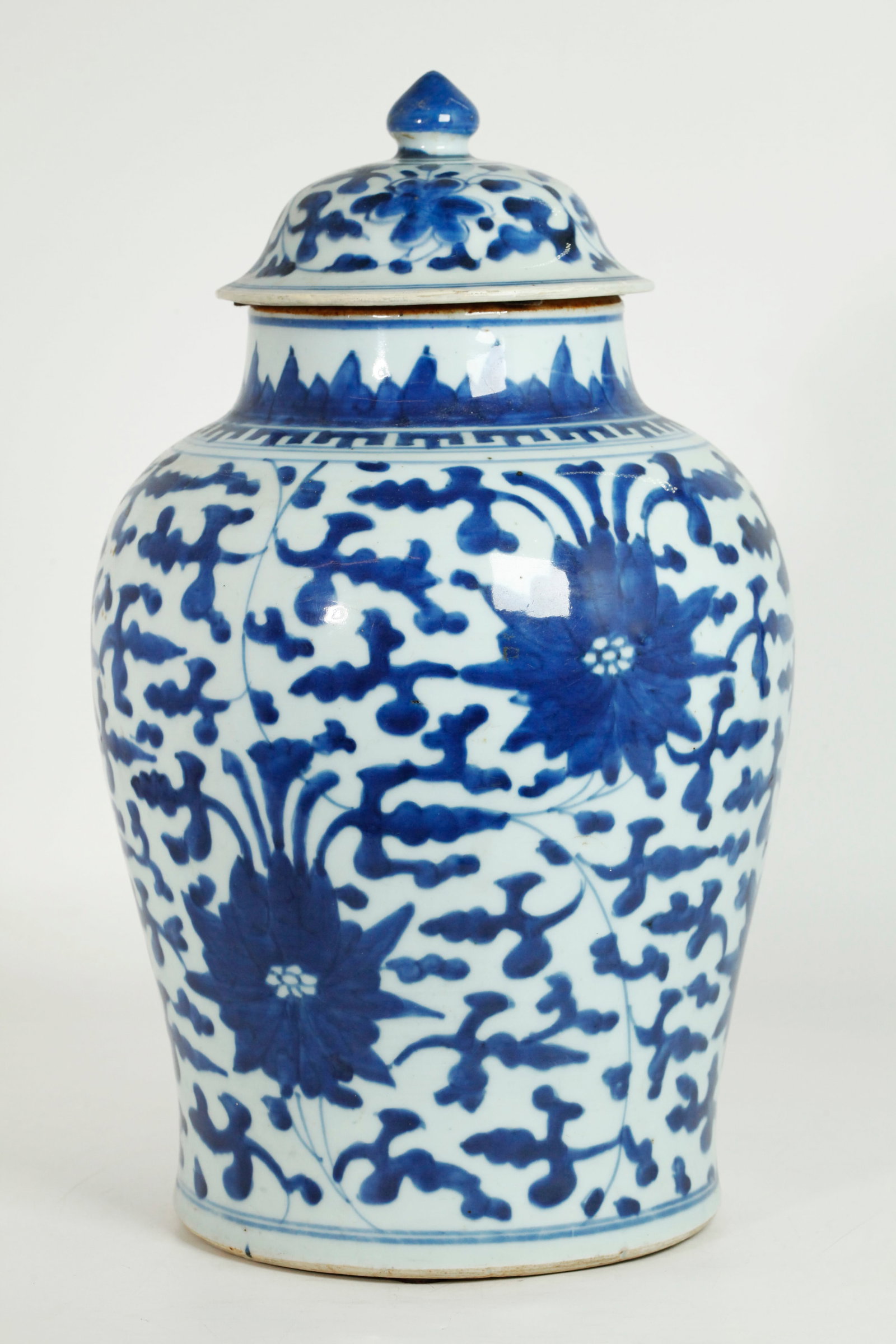Chinese Transitional Blue & White Porcelain Jar: Chinese Transitional 17th Century Blue & White Porcelain Jar with leaf & flower designs and upright petals around the mouth with edge in brown slip; the flat base unglazed, with original cover. Height