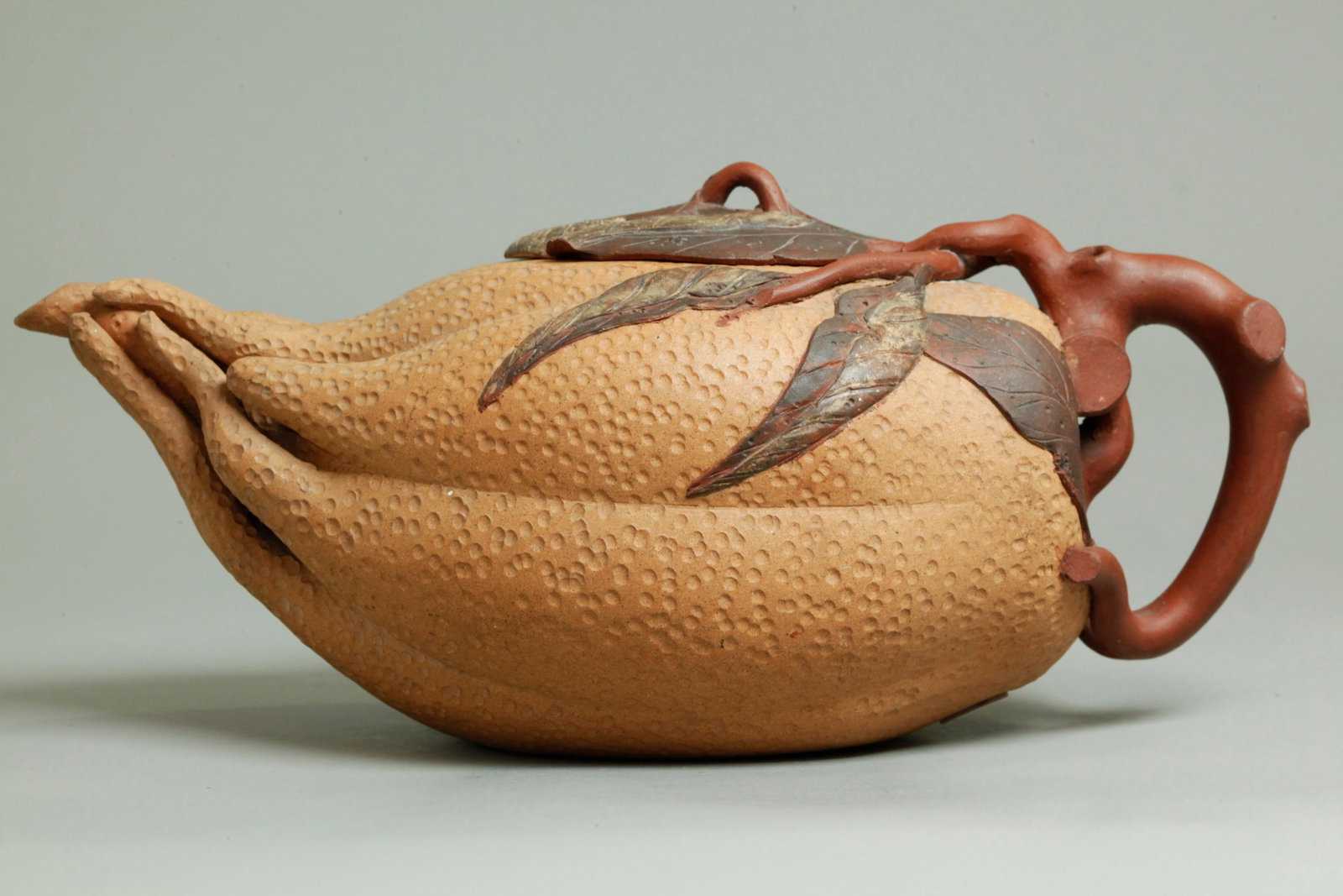 Chinese Yixing Zisha Buddha's Hand Citron Teapot: Chinese Yixing Zisha Buddha's Hand Citron Teapot formed in light clay with incised details with a brown clay stem handle attached to the back with dark brown incised leaves applied to the handle stems