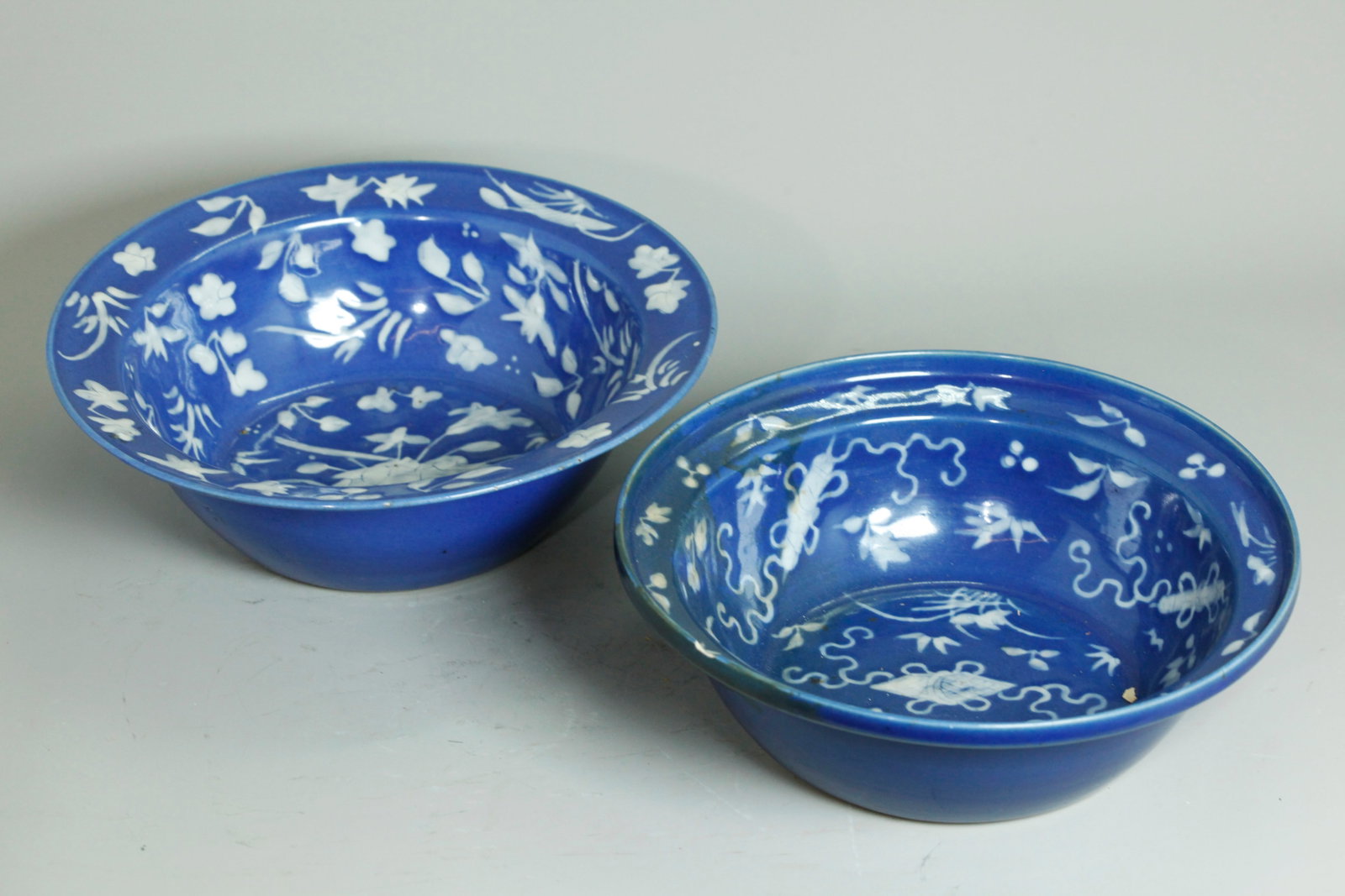 2 Chinese 19th C White Slip Blue Porcelain Bowls: 2 Chinese 19th C White Slip on Blue glazed Porcelain Bowls, the larger with leaves and flower sprigs to insides and a clear glazed recessed base, the smaller with auspicious objects and flower sprigs 