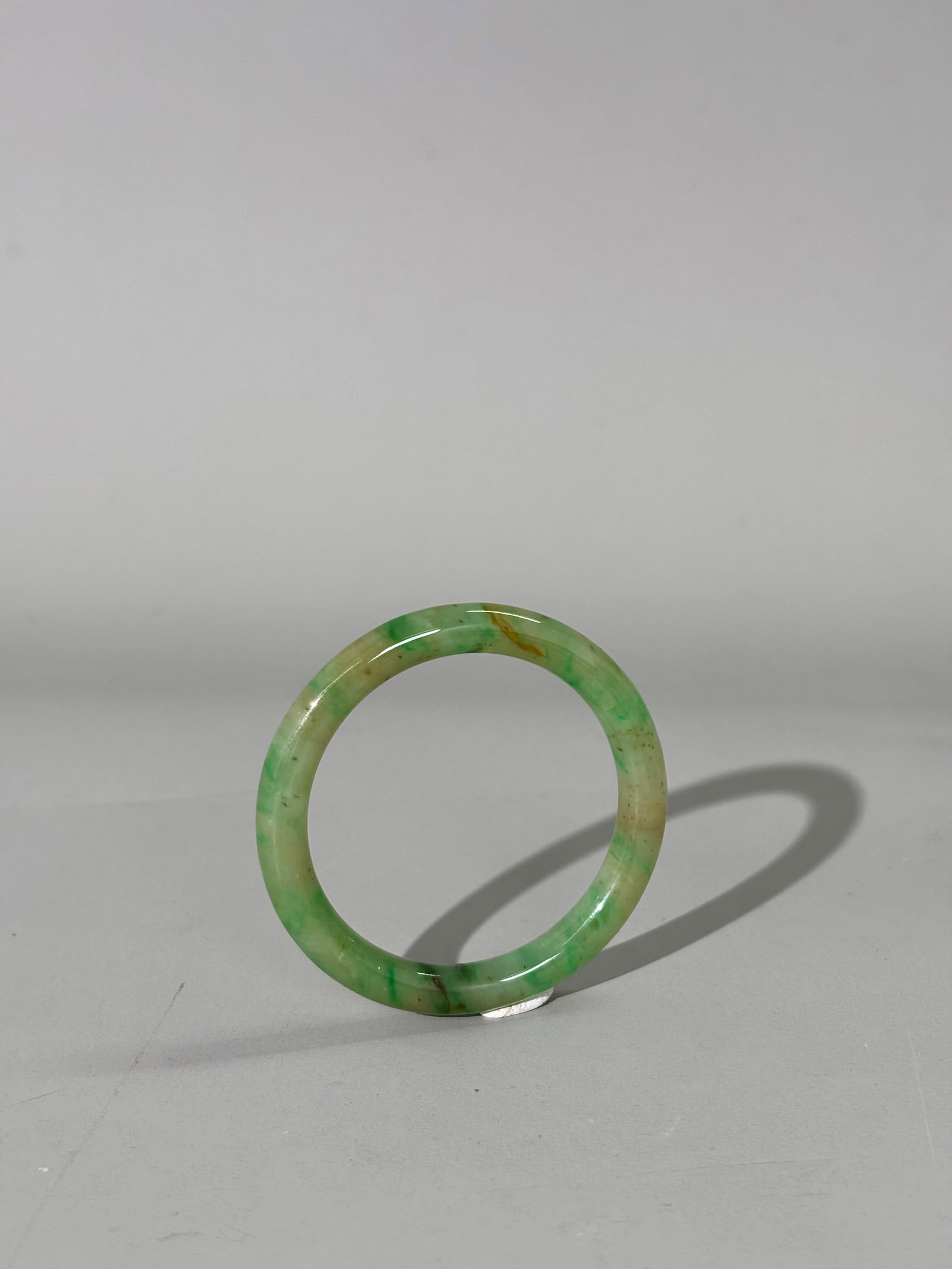Chinese Translucent Green Jadeite Child's Bangle: Chinese Translucent Jadeite Child's Bangle in pale green with apple green to russet & brown spot inclusions. Diameter 61.3mm. X inside diameter 47mm.