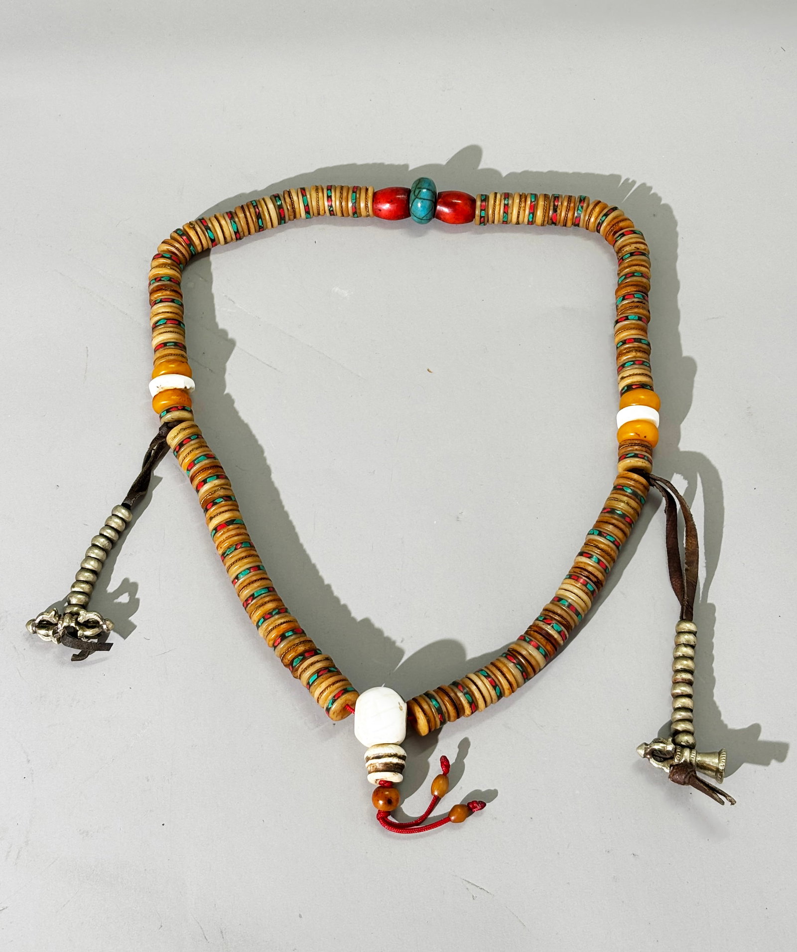 Tibetan 108 Old Bone Kapala Buddhist Rosary; 236G: Tibetan 108 Old Bone Kapala Buddhist Rosary, the beads alternately inlaid with tiny flakes of turquoise & coral or twisted brass wire and hung with additional amulets. Total weight 236 grams. Length 2
