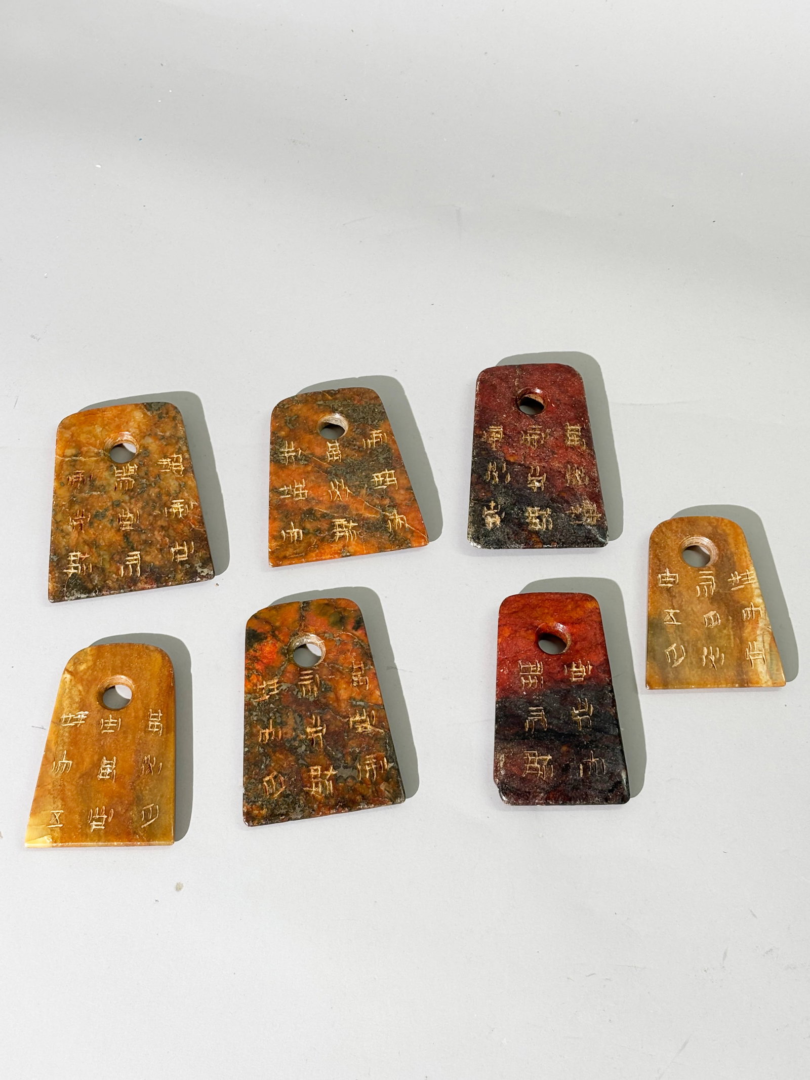 7 Chinese Jade Calligraphic Musical Chimes: 7 Chinese Jade Calligraphic Musical Chimes or Talismanic Pendants in dark brown to russet each wheel carved with inscriptions to both sides with large irregular tapered holes drilled from both sides t