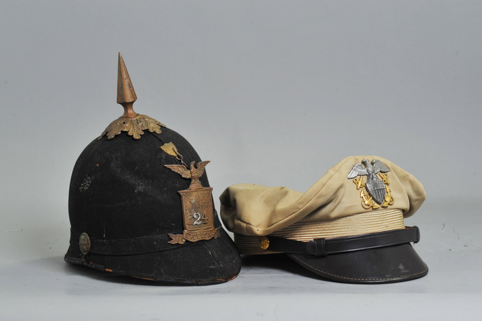 2 Hats: Antique 24 NY Infantry Shako; Khaki Navy: 2 Hats: Antique 24 NY Infantry Shako made by Ridabock & Co New York, possibly Civil War; together with a vintage Khaki Navy Officer's hat size 7 1/8, with black brow strap, possibly WW2. Height of lar