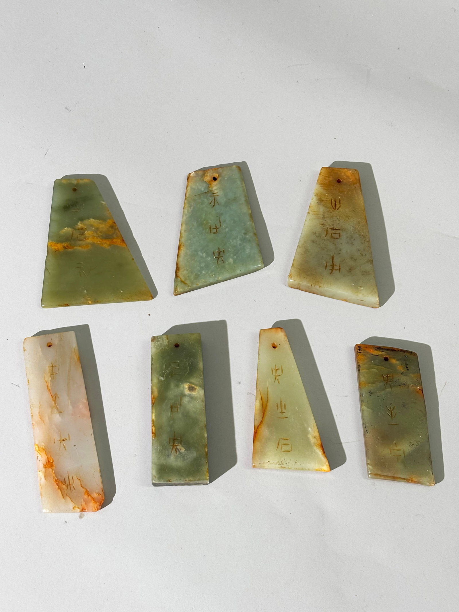 7 Chinese Jade Calligraphic Musical Chimes: 7 Chinese translucent Jade Calligraphic Musical Chimes or Talismanic Pendants in green to warm white with russet passages or inclusions, each wheel carved with inscriptions to 1 side, the reverse poli