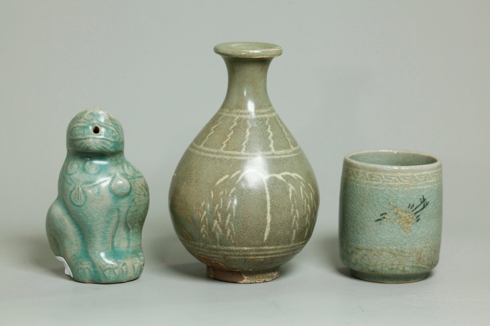 3 Korean Celadon Porcelains; 2 Inlaid, 1 Carved: 3 Korean crackle Celadon Porcelains; a small vase or oil jar sanggam inlaid in cream slip forming 2 Willow Trees and decorative bands, the base part glazed with kiln grit and a small tubular cup with 