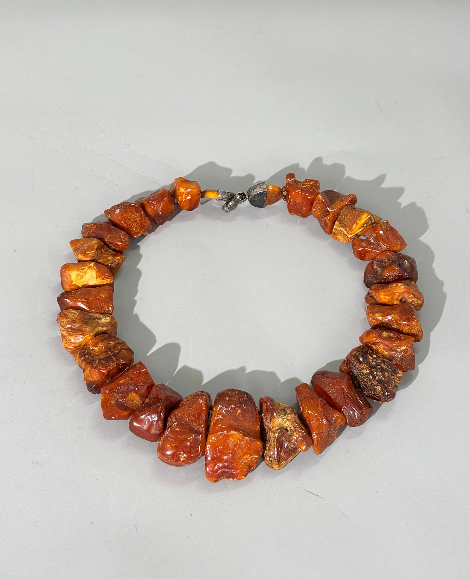 27 Lg Butterscotch Amber Irregular Beads; 162G: 27 Large Butterscotch Amber Irregular polished Beads strung together with knots on 2 parallel cords to form a flat bib-necklace; the closure in silver. Total weight 162 grams. Total length 19 1/2''