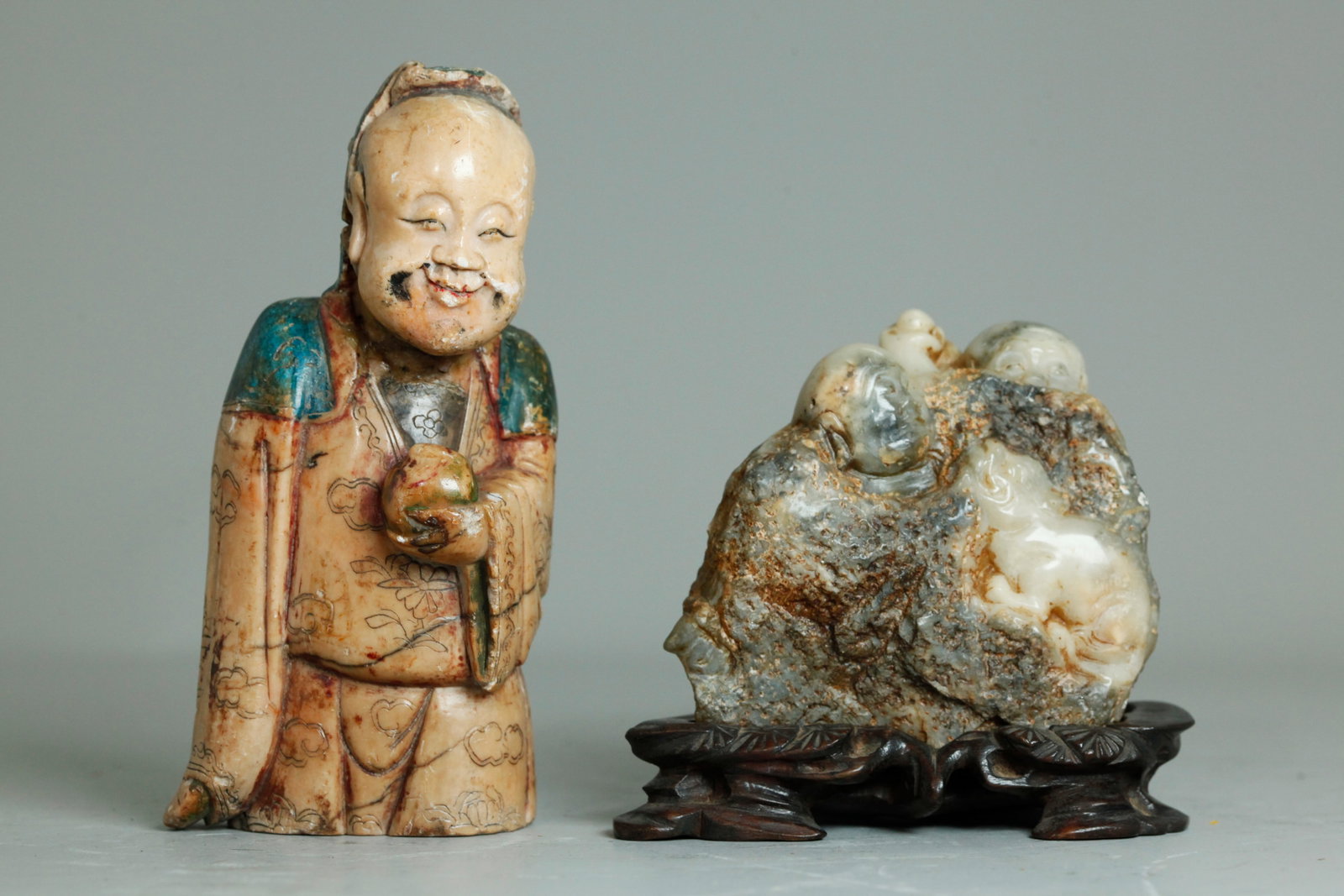 2 Chinese Qing Shoushan Soapstone Figural Carvings: 2 Chinese Qing Shoushan Soapstone Figural Carvings, the earlier carving in pale ochre of the upper portion of an Immortal with Peach in his hand, embroidery carving to the gown and blue coloring to