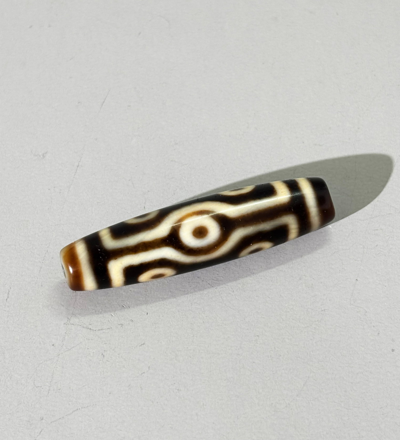Tibetan Dzi "Seven Eye" Bead; 11.5G: Tibetan Dzi "Seven Eye" Bead with irregular center hole drilled from both sides. Total weight 11.5 grams. Length of bead 1 7/8 inches.