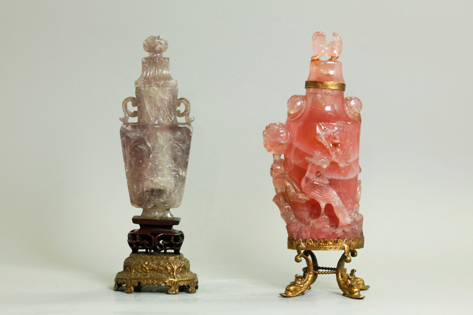 2 Chinese Carved Urns Rose Quartz Amethyst Matrix: 2 Chinese Qing Dynasty carved & covered Urns: the larger in hollowed striped translucent Rose Quartz carved with a Phoenix Bird to front, Peonies to 1 side and a Lingzhi to the other side and Peony bl