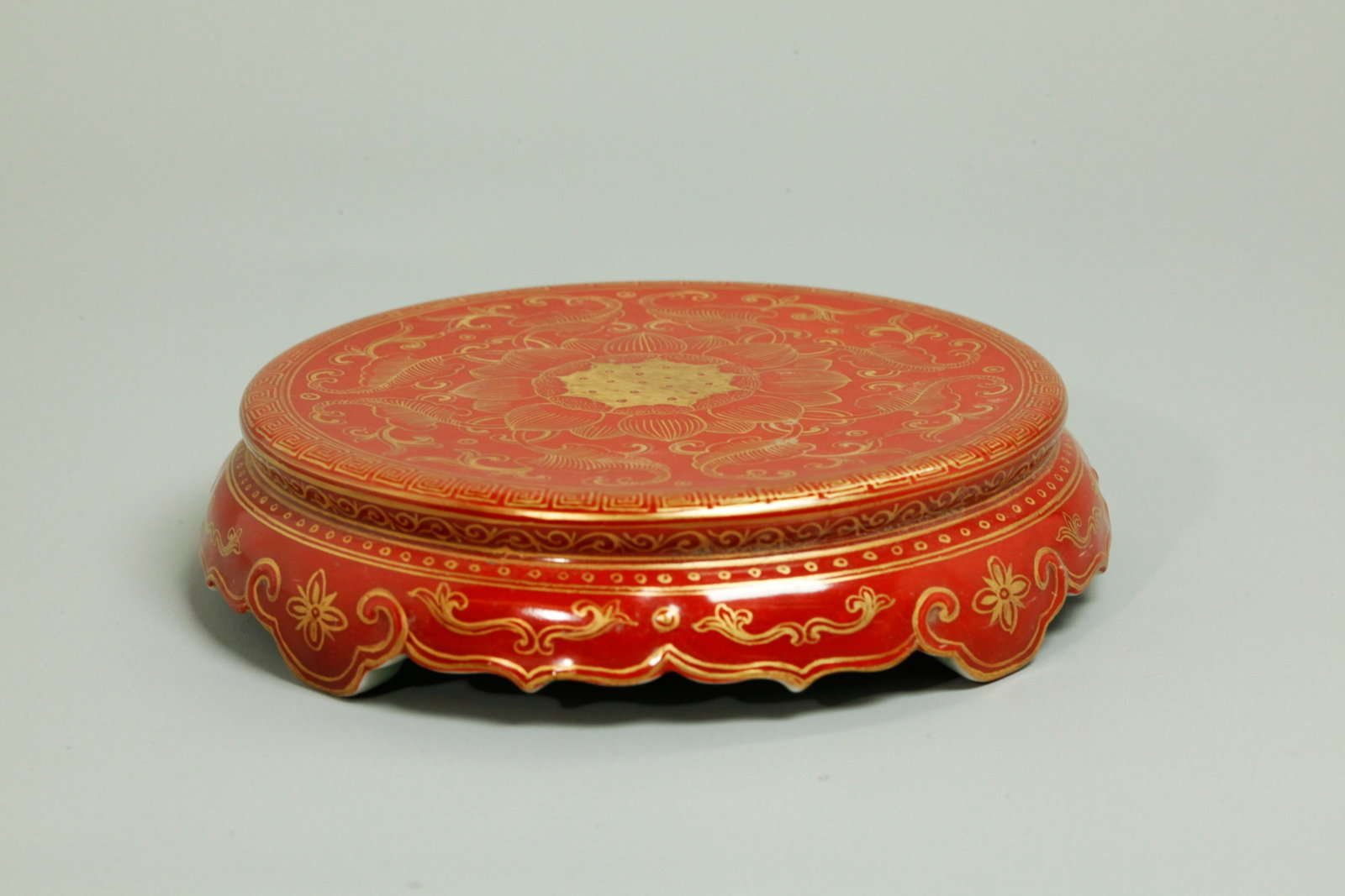 Chinese "Coral" & Gold Porcelain Stand: Chinese Iron Red "Coral" ground Porcelain Stand with a Lotus Pod & Petal center with leaves around a thunder cloud border, the base shaped with 4 Ruyi Head feet and the concave base in turquoise with 