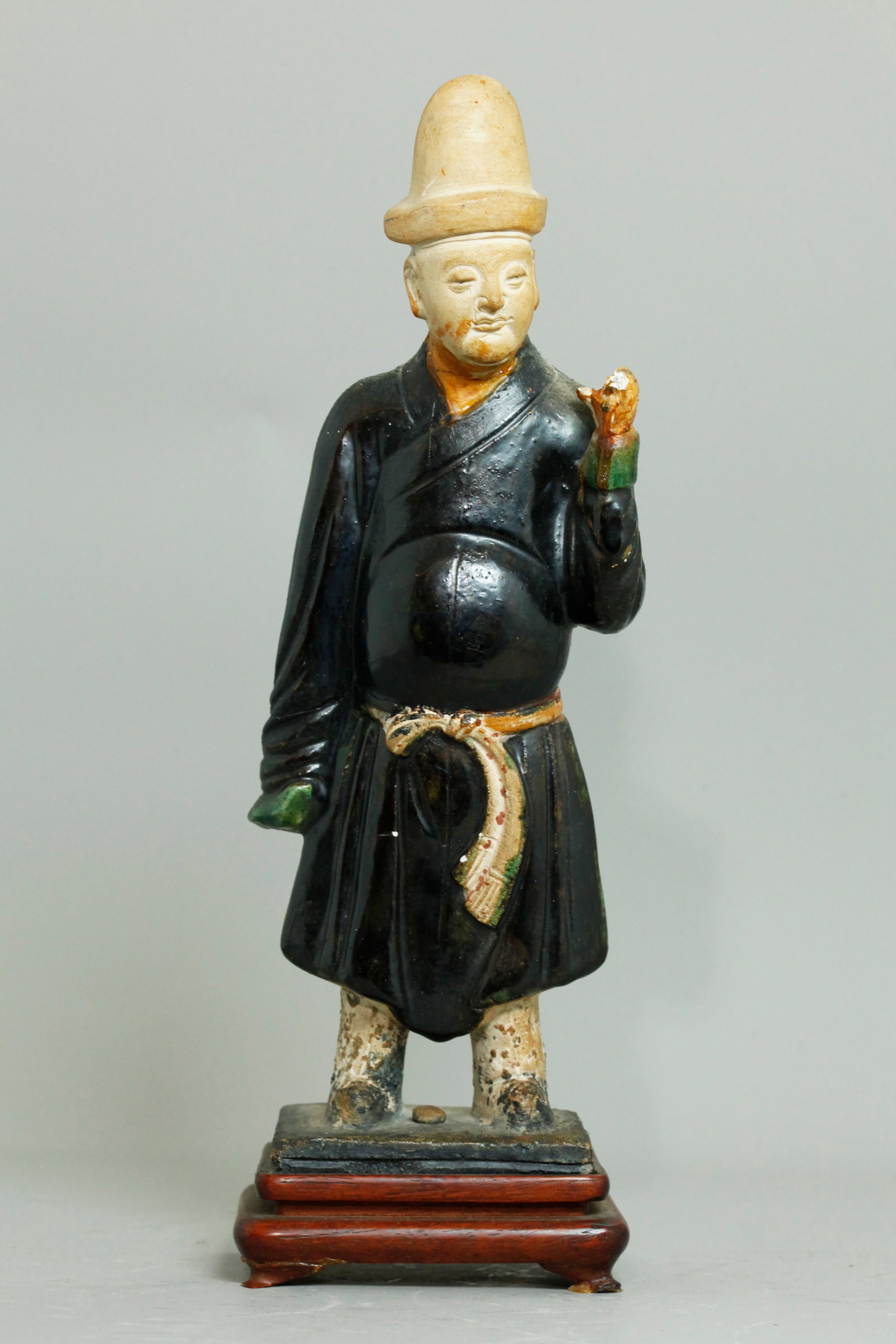 Chinese Ming Glazed Pottery Attendant Figure: Chinese Ming Dynasty Glazed Buff Pottery standing Attendant Figure, with well-detailed unglazed face in a tall hat, with robe in dark purple glaze with green glazed sleeve ends; the original rectangul